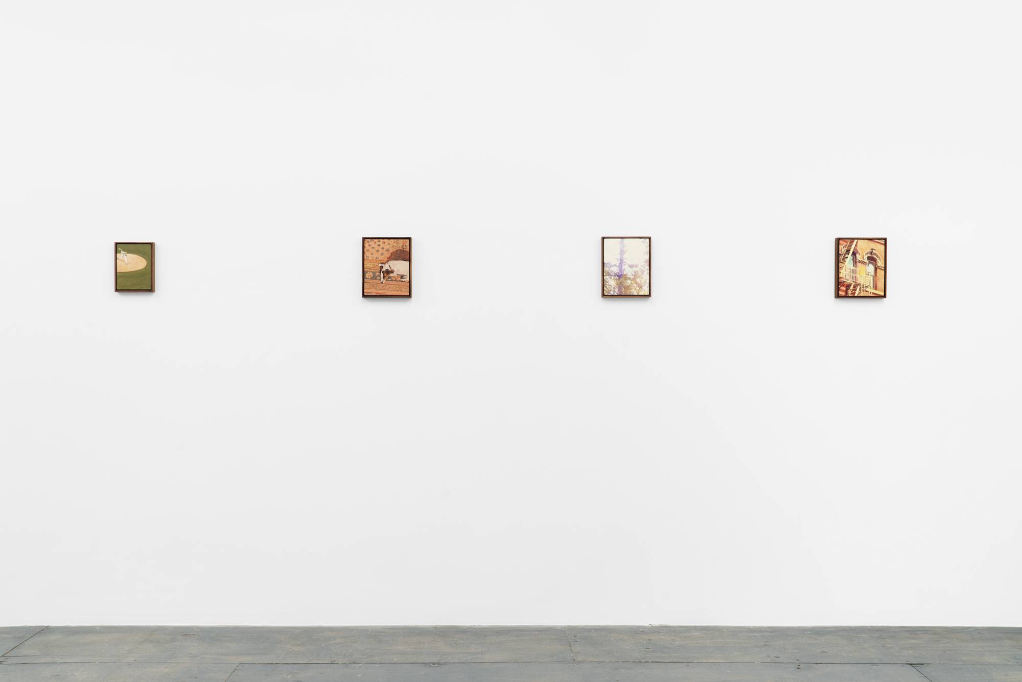 Four framed paintings are displayed in a line on a plain white wall, with a grey painted wood floor below. The artworks depict various scenes, including a baseball player, a dog, trees, and architectural elements.