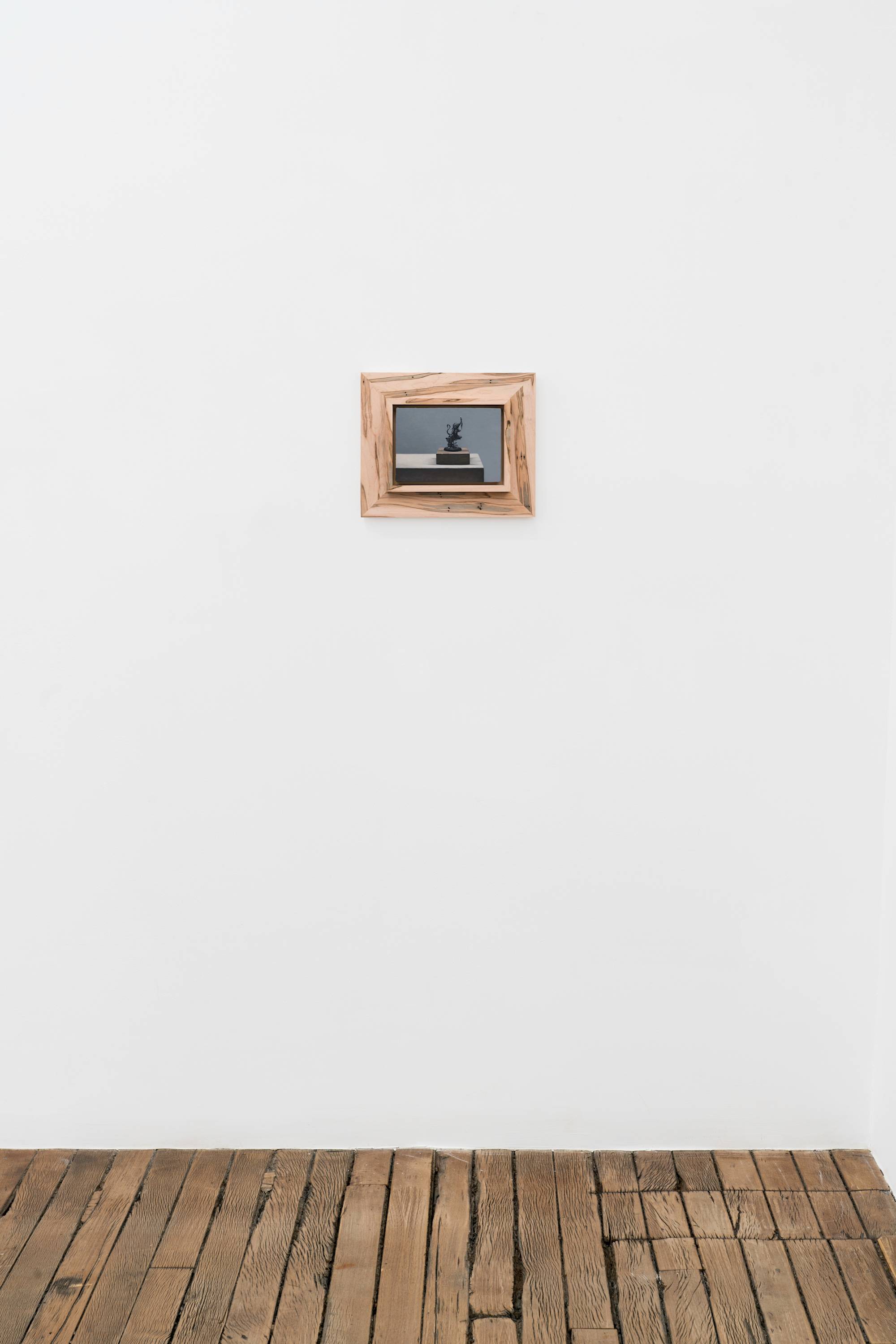 Ian Miyamura painting depicting an unpainted Warhammer figure sitting on a wood block against a grey background hangs in a gallery above a wood floor. The painting is mounted to a wood frame made by the artist.