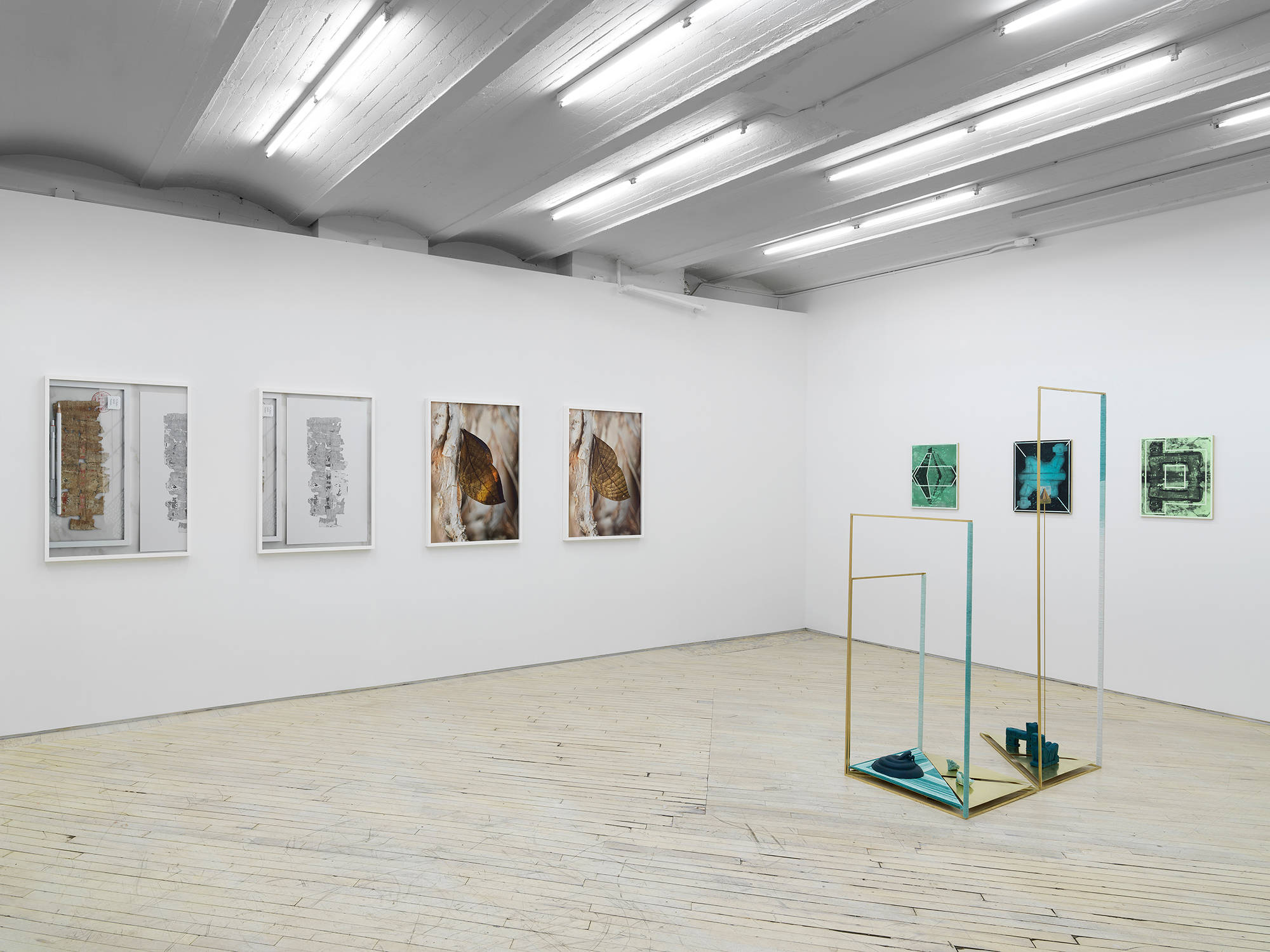 Installation view of the exhibition Throughline at Bureau featuring a series of four digitally rendered photographs by Jeffrey Stuker on the left and a sculpture and three panel paintings by Claudia Peña Salinas on the right.