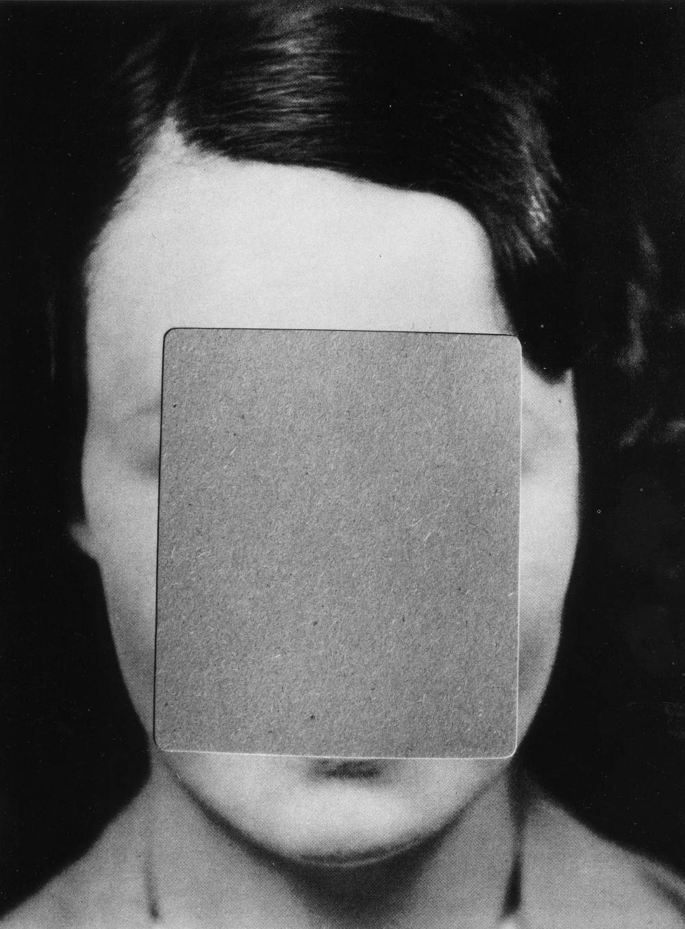 Close up black and white image of a woman's face with the majority of the facial features cut away in the shape of a rectangle that is filled with a second gray image.