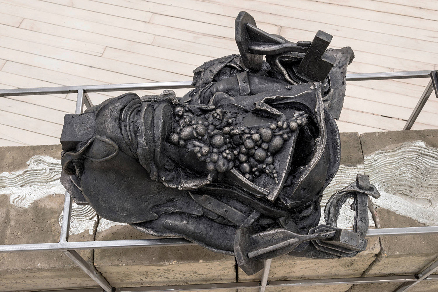 Detail shot of small cast iron sculptures on top of the metal frame which covers a concrete and pewter base built of blocks with a pewter river carved into it.