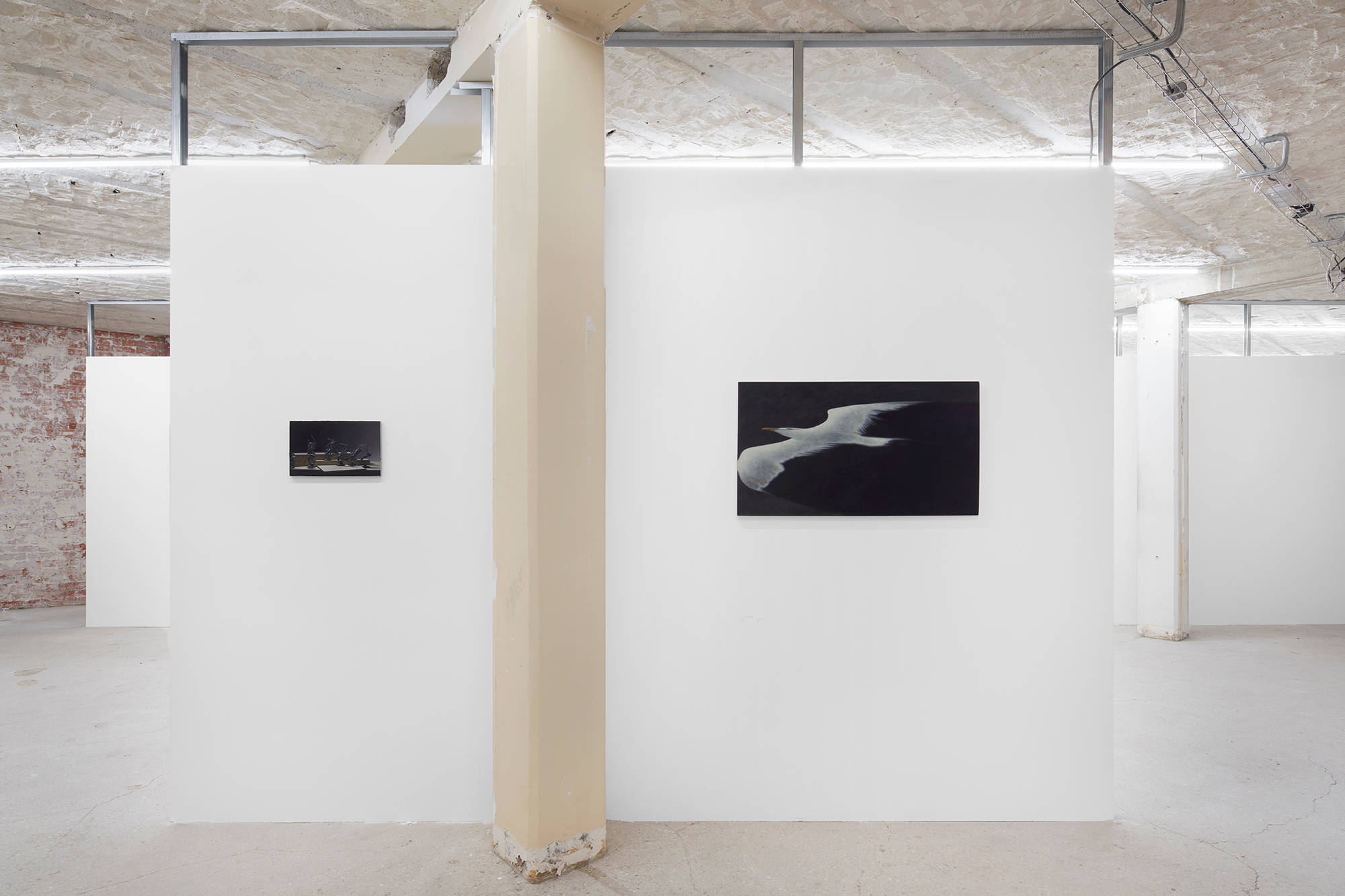 Installation view of Ian Miyamura paintings at the Paris Internationale fair, with various sized paintings hanging on brick walls.