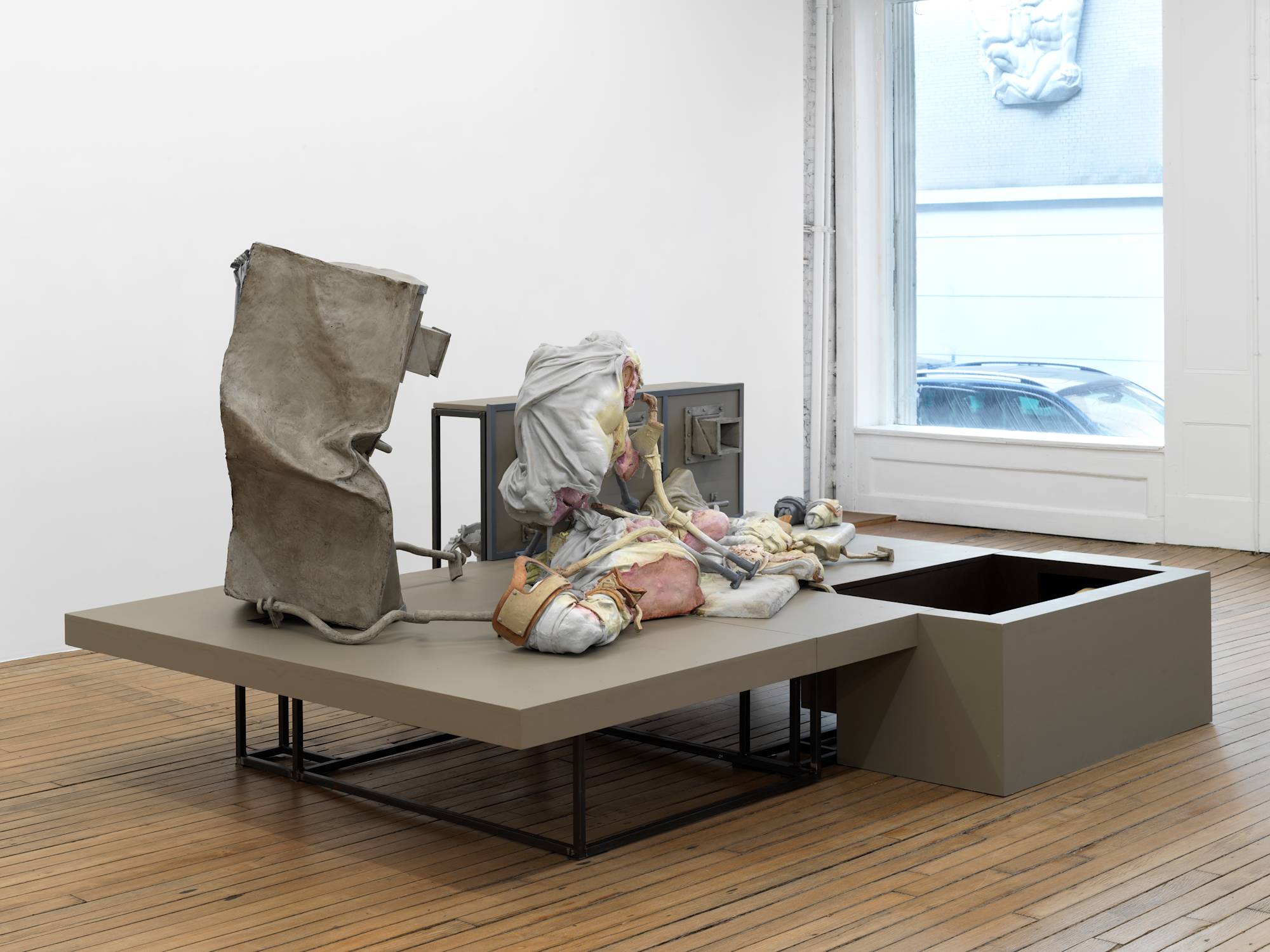 A large floor-standing sculpture depicting a combination of abstracted human forms and devices, combined with steel structures that resemble cages.