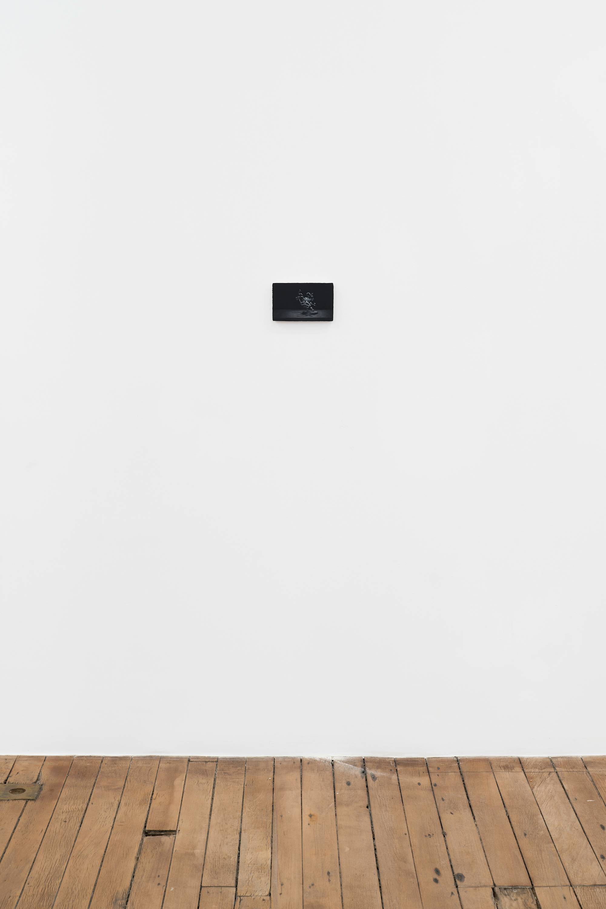 Ian Miyamura painting depicting an unpainted Warhammer figure against a black background hangs on the wall of a gallery.