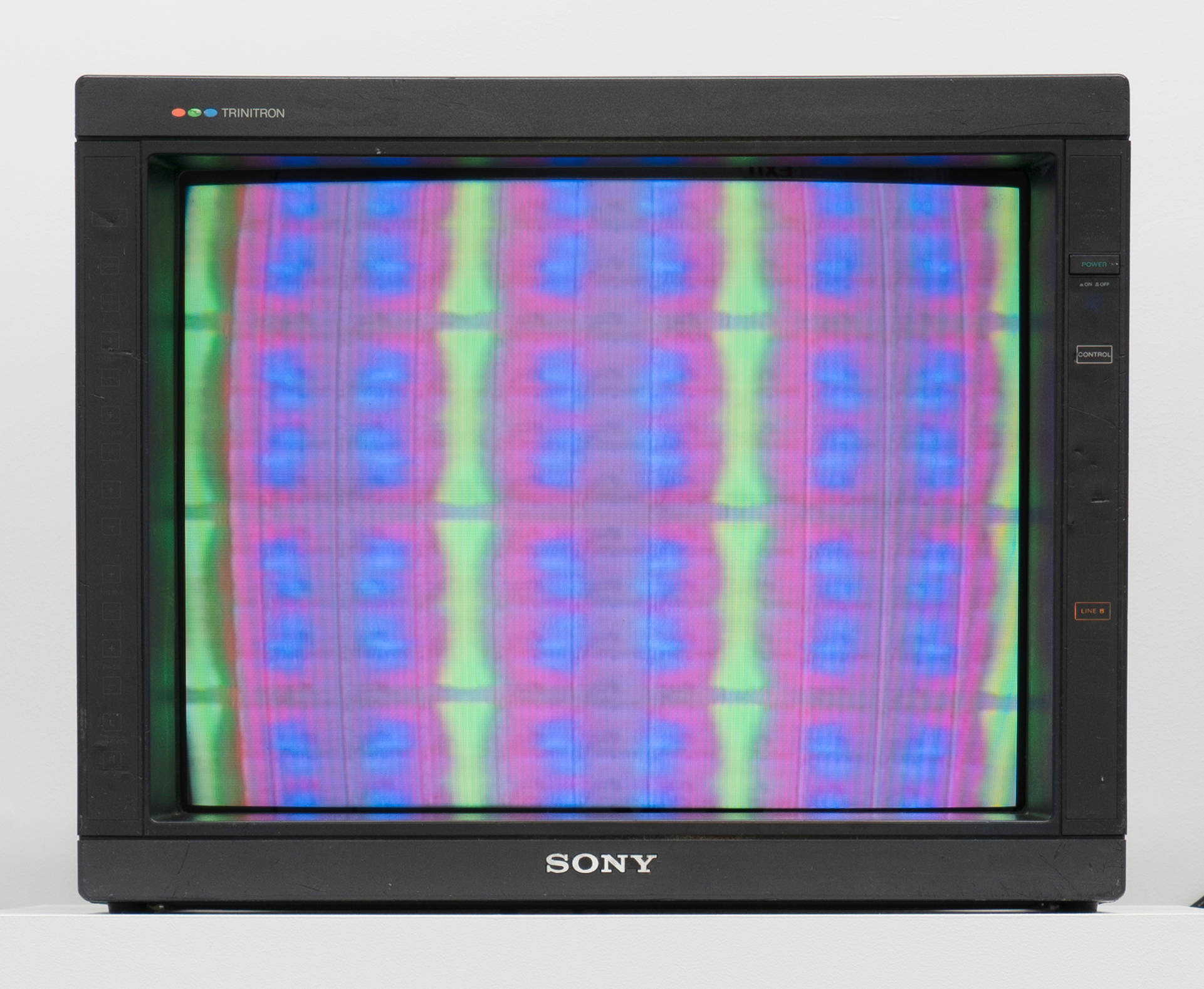 A tv monitor displaying a still image blurred colors in a grid pattern taken from an animation.