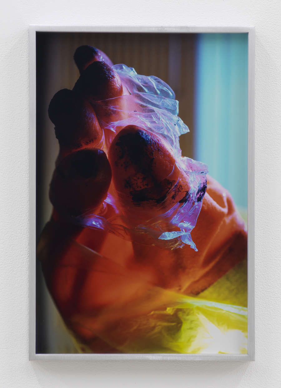 Image of a rainbow colored dish glove, finger together, bound with a clear tape like substance occupying the majority of the image.