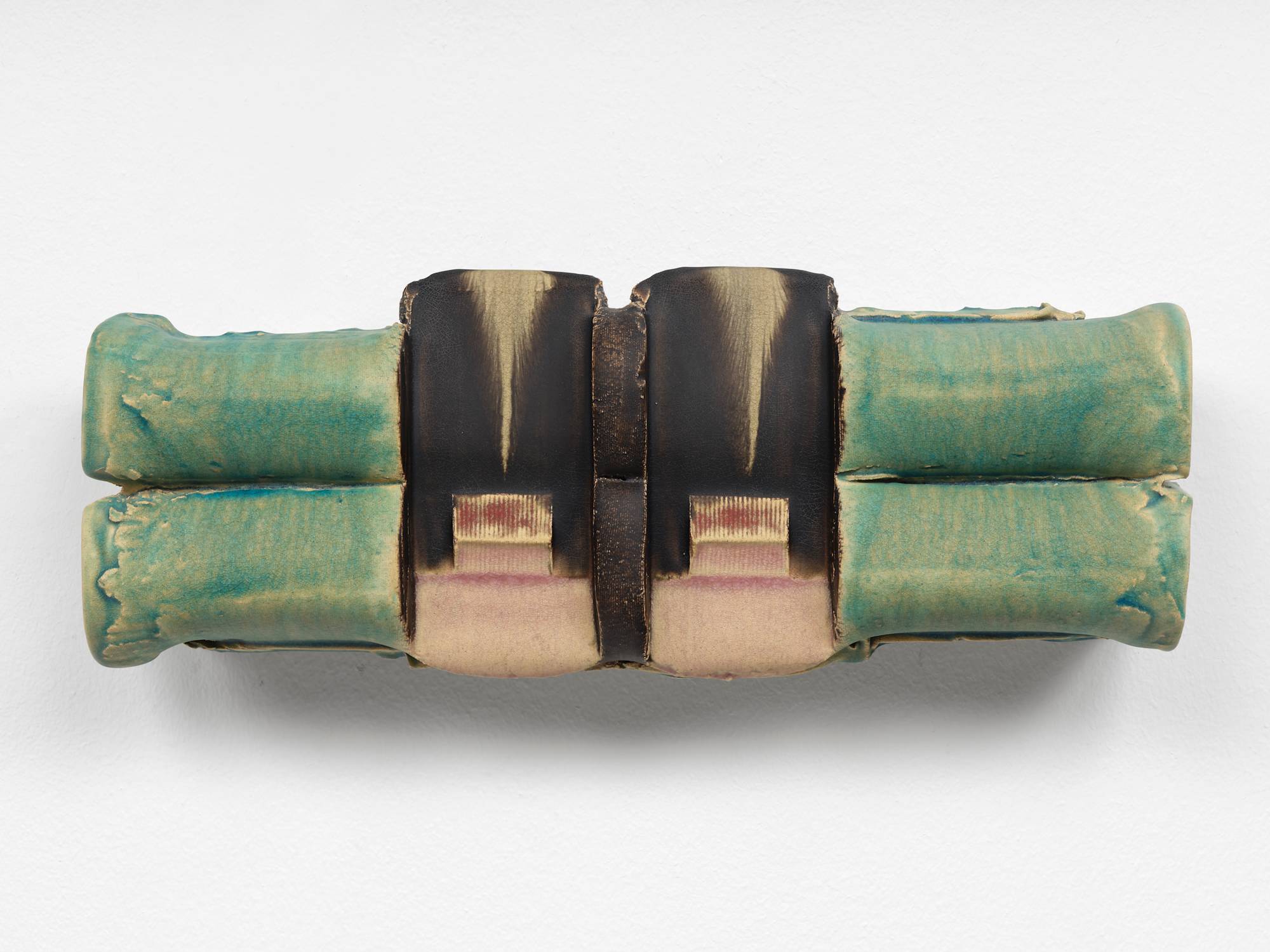 A symmetrical ceramic sculpture composed of two horizontally stacked cylinders that have been perpendicularly stamped twice towards the center and glazed in hues of aqua, pink, brown, and red.