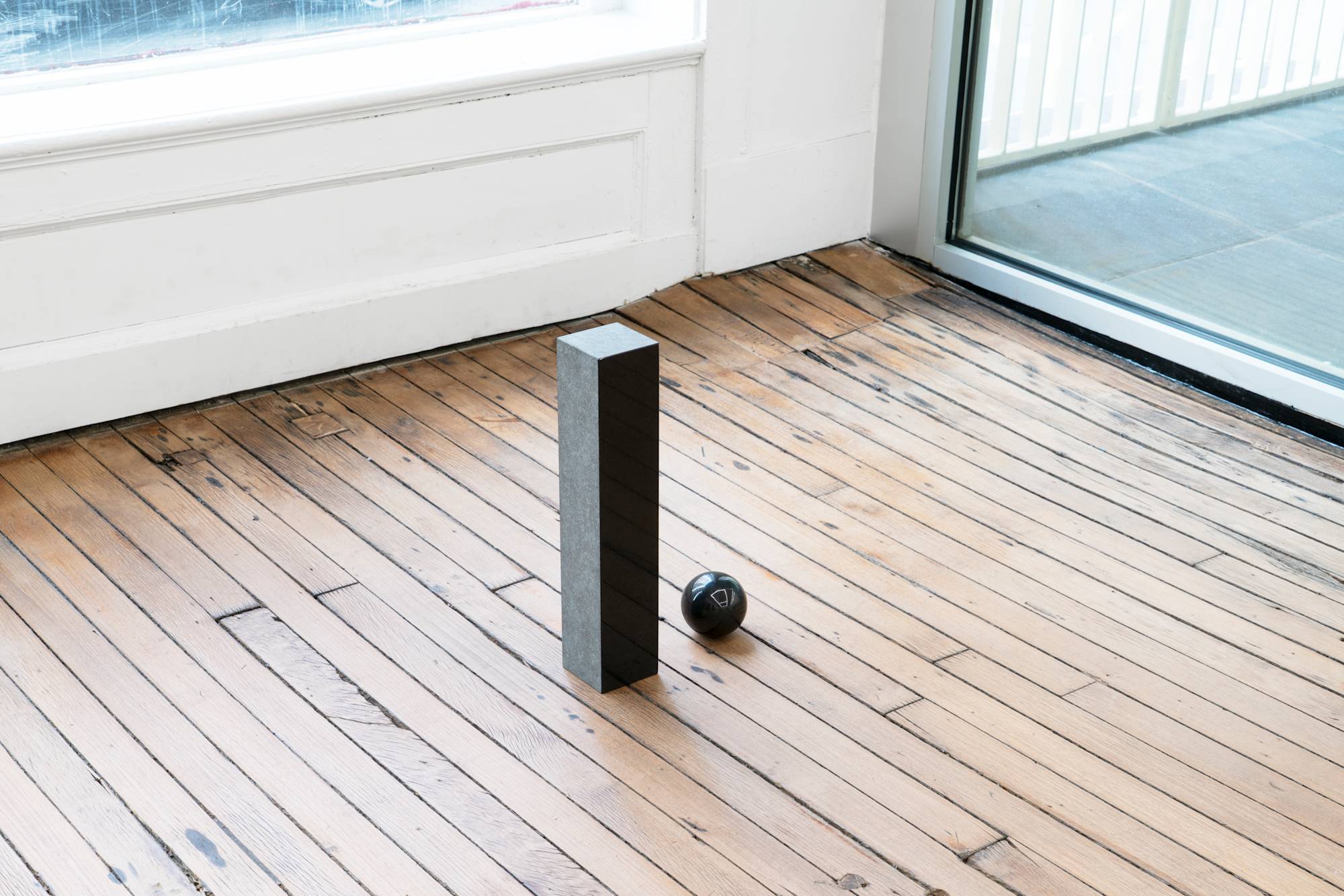 A granite sculpture of an "i" that's tittle has fallen out of suspension and to the floor.