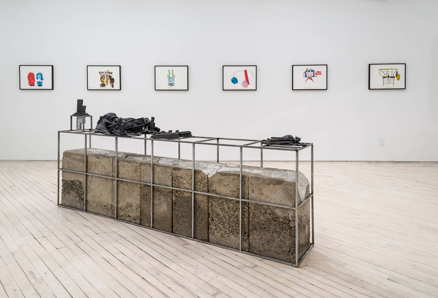 Installation view of the exhibition in the main space. In the foreground, a low concrete and metal sculpture by Lionel Maunz, behind it on the white wall a suite of six colorful ink drawings by Christine Rebet.