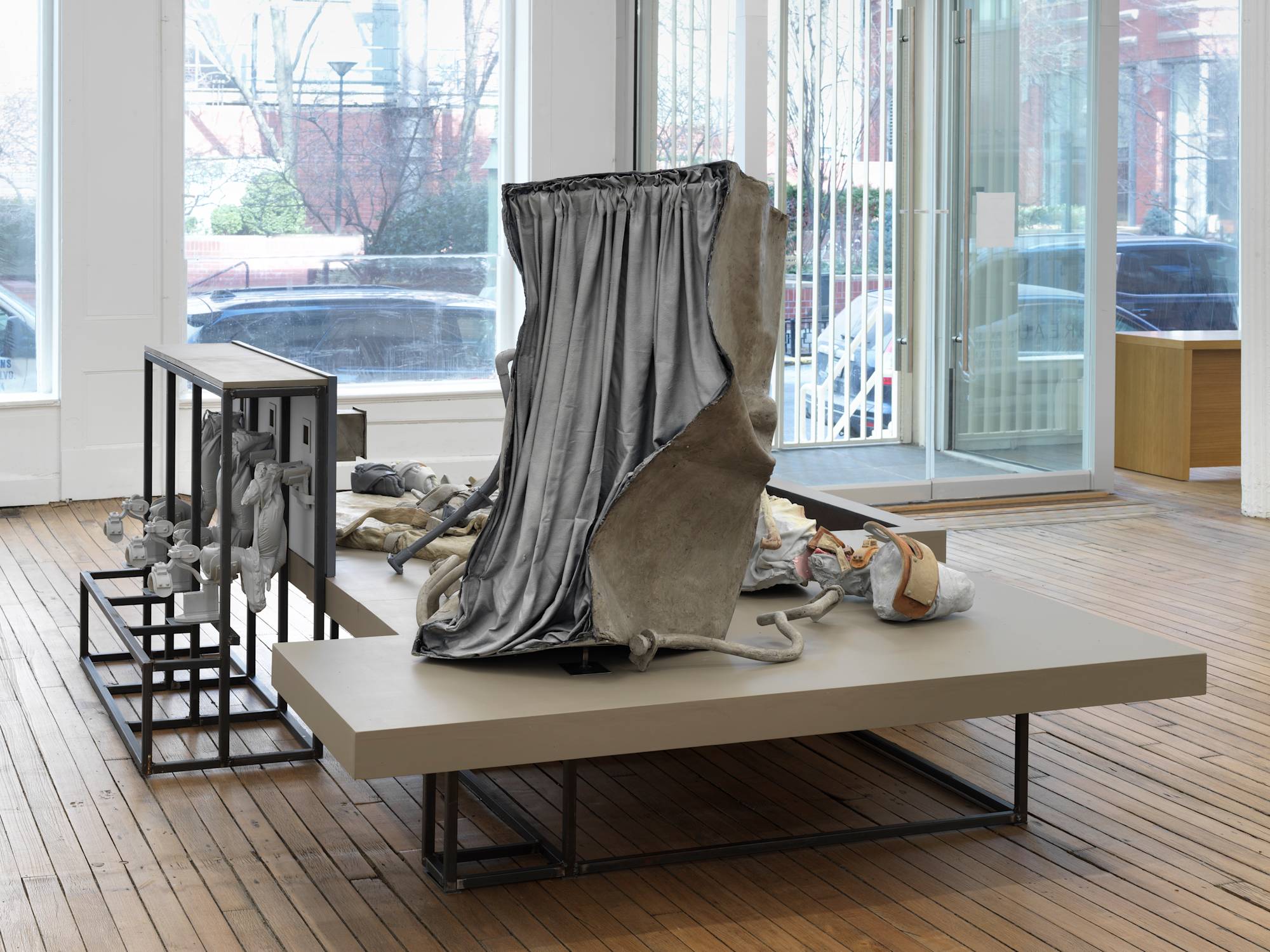 A large floor-standing sculpture depicting a combination of abstracted human forms and devices, combined with steel structures that resemble cages.