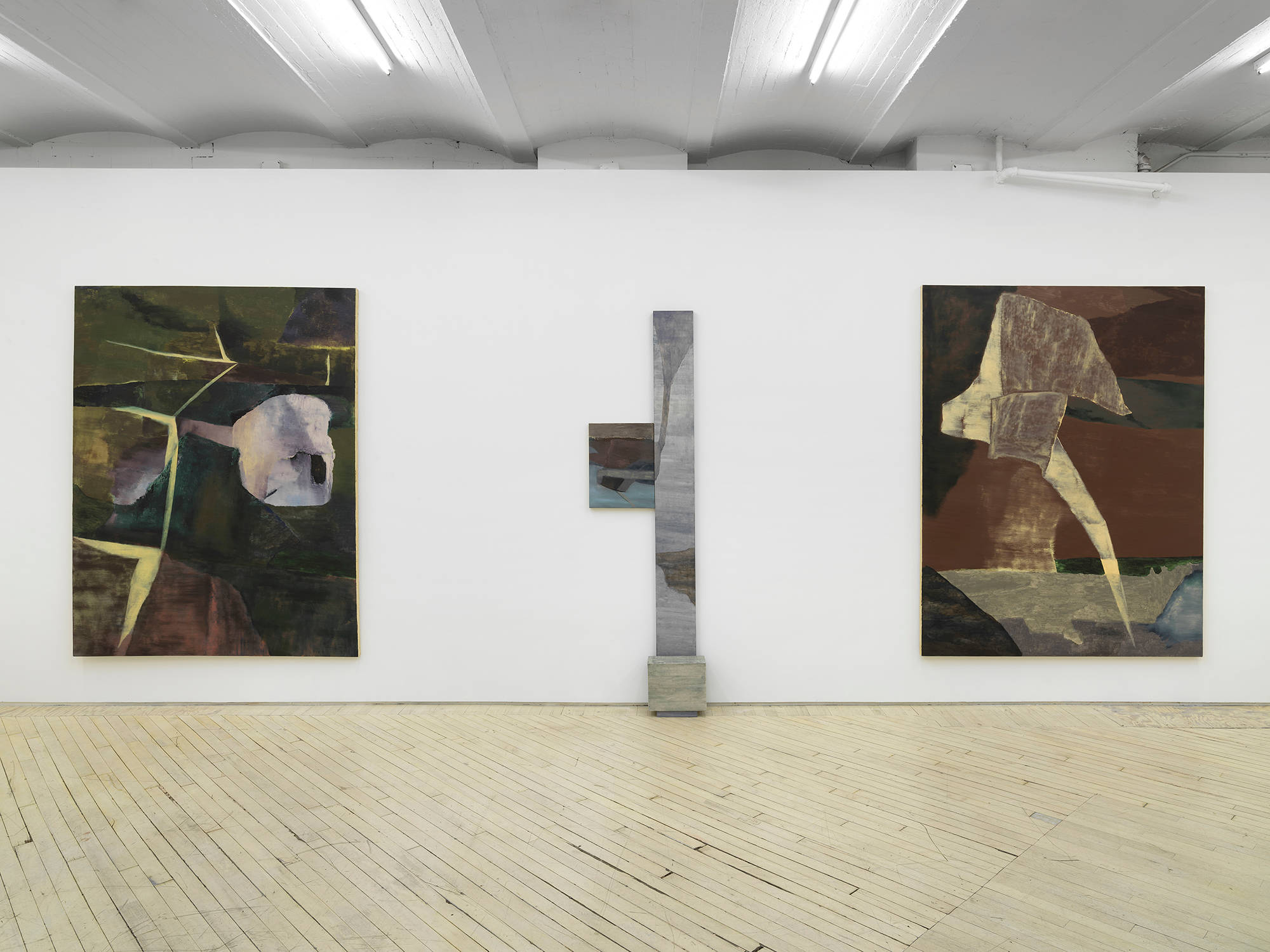 Two large abstract paintings installed in a gallery with a vertical leaning painting and sculpture in the center. Each are rendered in muted palette of browns and greens, predominantly.