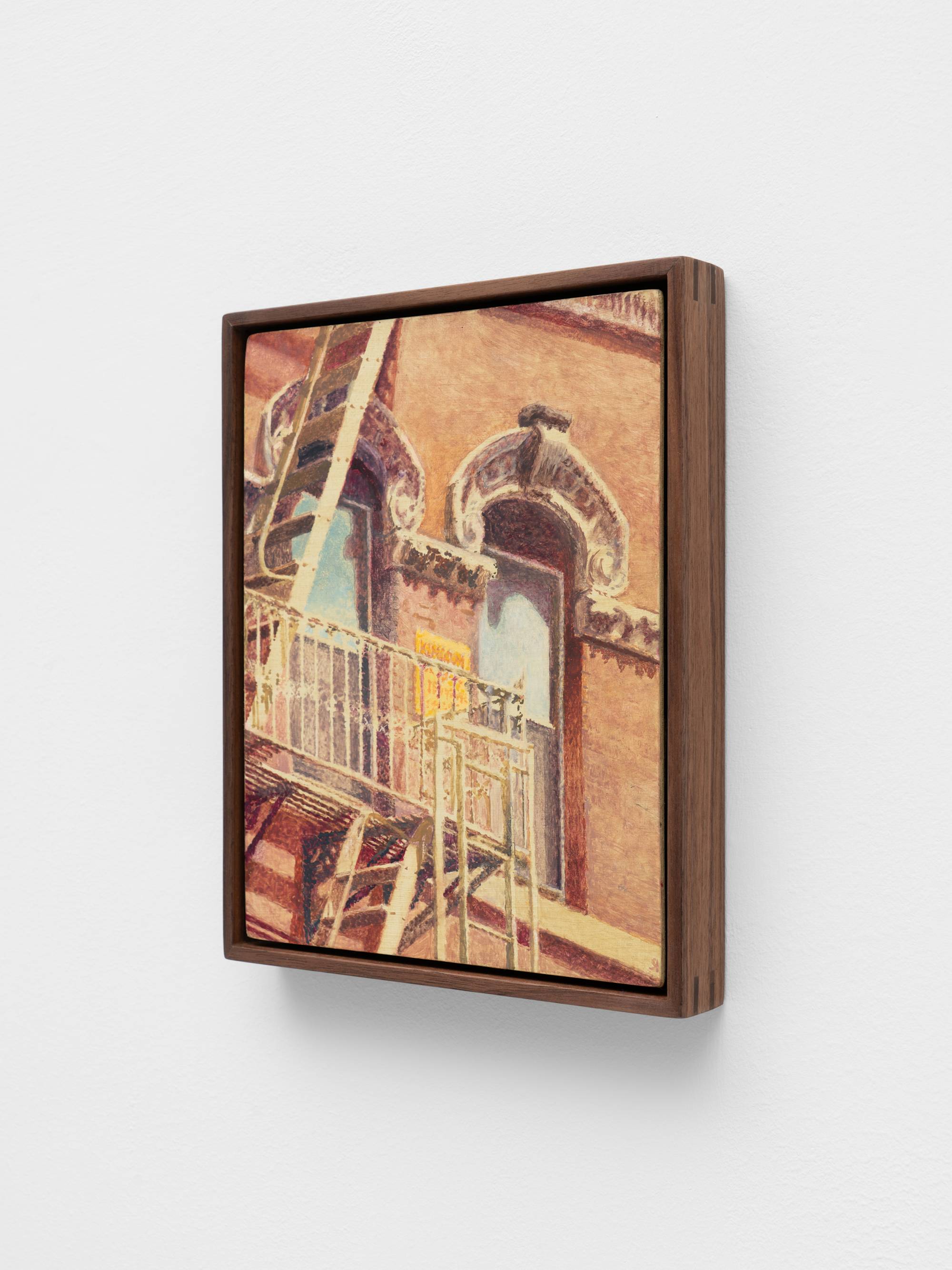 A small, dark wood framed, painting of a cropped view of a fire escape in Chinatown NYC hangs on a white wall.