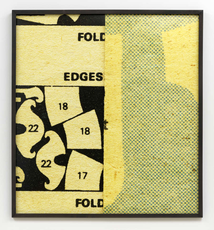 Image of a photograph in a black frame, the photograph depicts an up close look at a vintage sewing pattern. The pattern's paper is yellowed and coarse, appearing to be folded in half down the middle. The pattern is cropped and visible are a series of numbered shapes and the words "Fold, Edges, Fold"