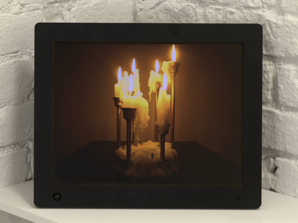 A digital screen projecting an image of several lit candles. 