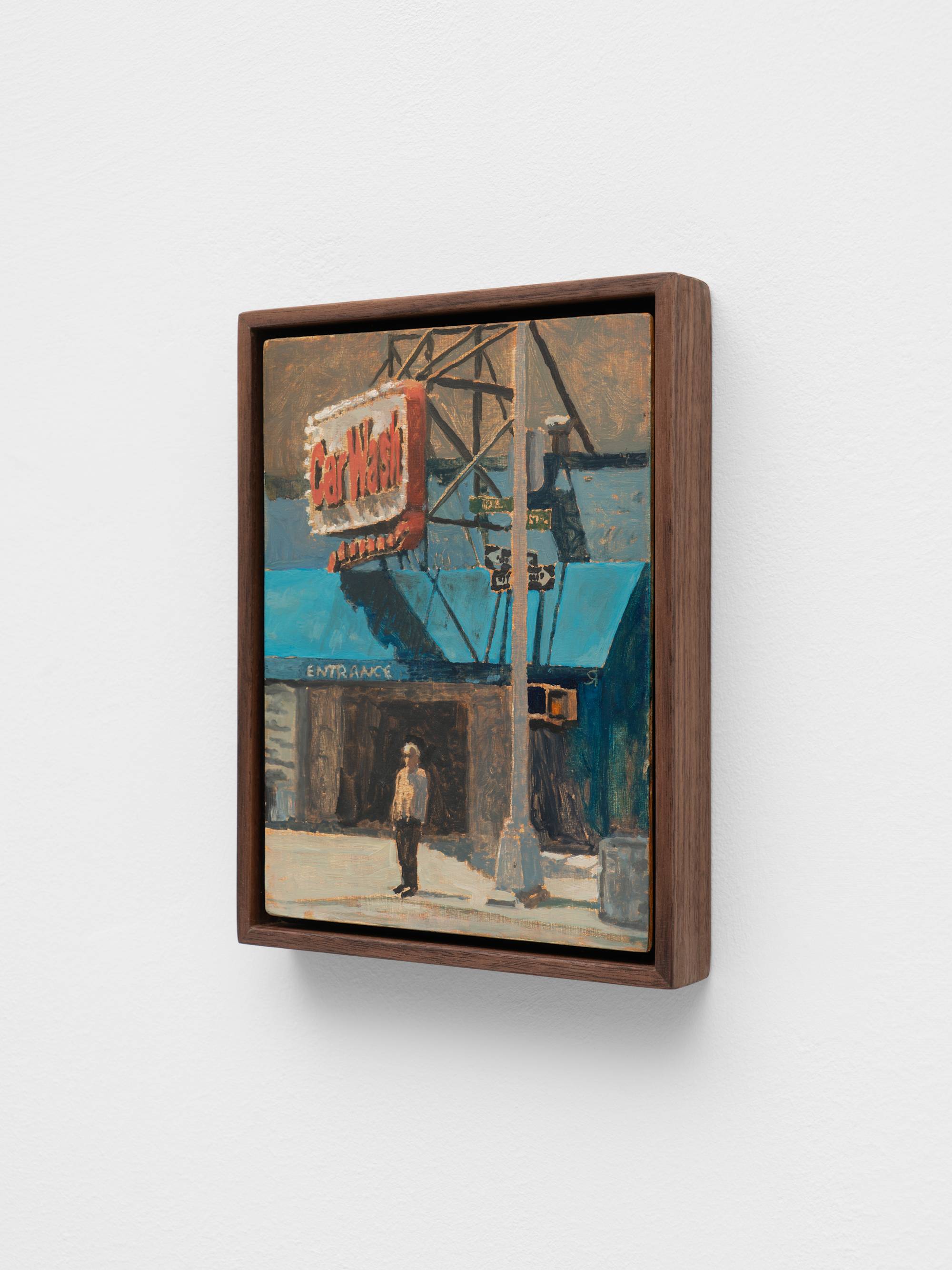 A small, dark wood framed painting of a figure standing beneath a car wash sign on a street corner.