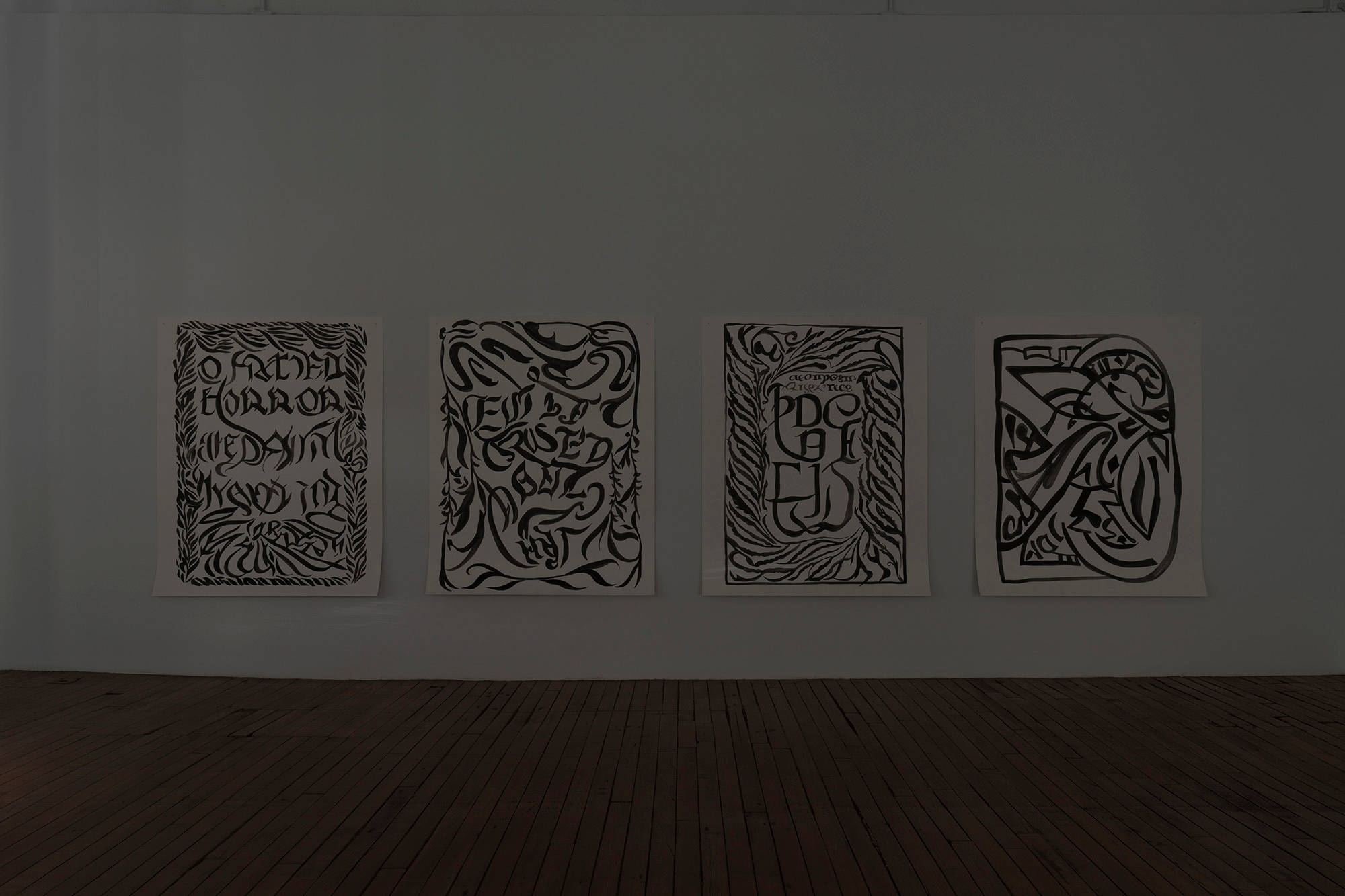 Four large ink drawings on paper hang on the wall in a dark gallery.