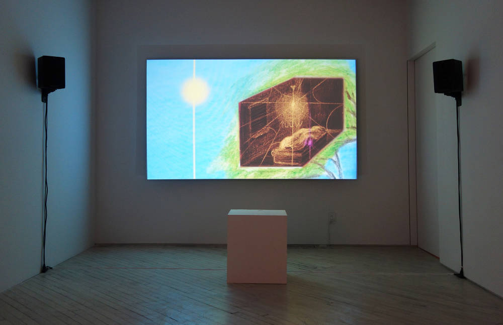 Installation view of a projected film against a wall showing a blue field with a white orb and an interior scene of a bedroom. There are speakers hanging on the walls on either side of the projection and a projector box is on the floor.