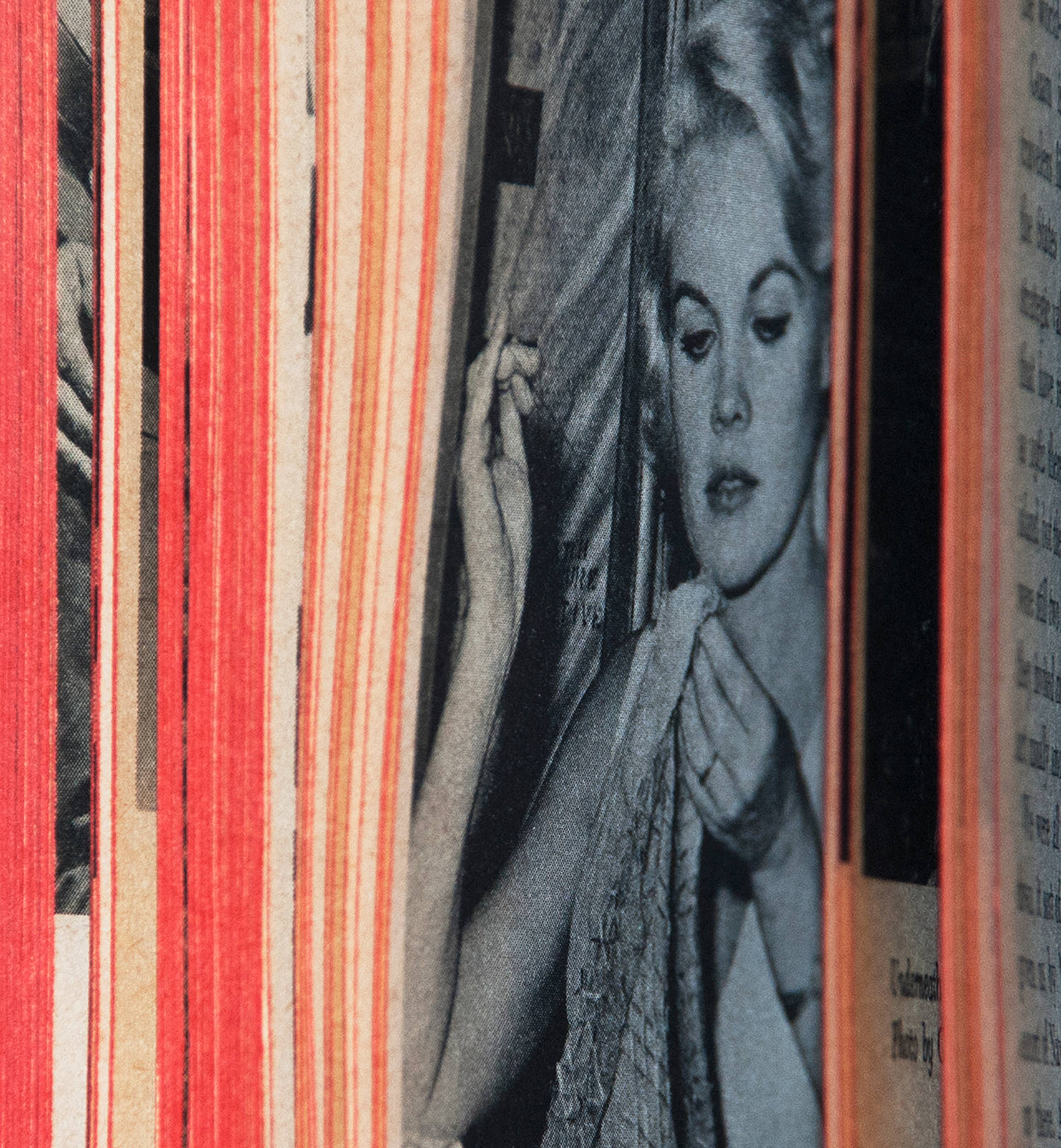 Photograph of an open paperback book with red dyed page edges showing fanned out pages and at the center a black and white photograph within the pages of of a blonde 1960's starlet sewing some fabric, pulling the needle.