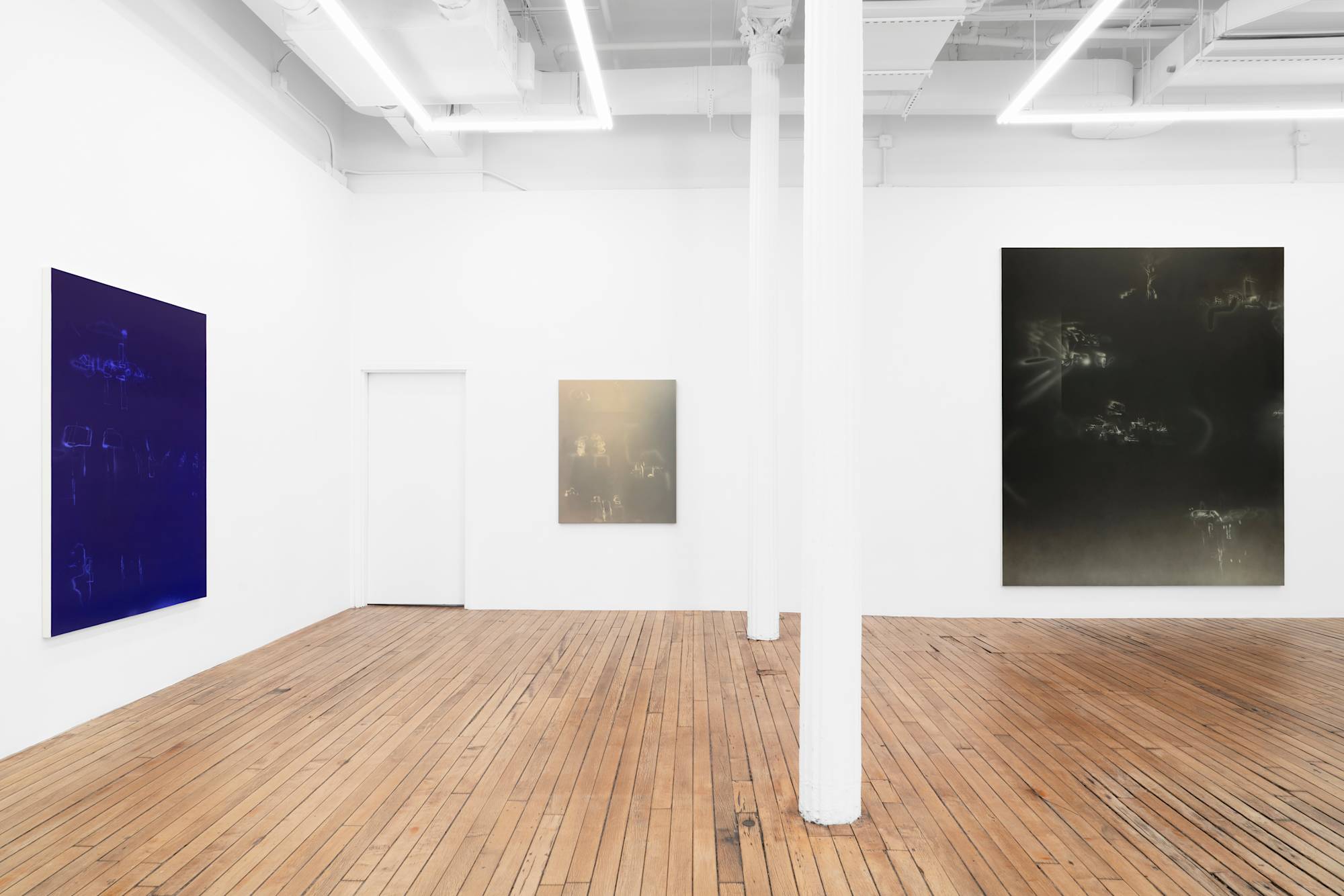 In a large gallery space, three vertical, abstract paintings depicting a range of airbrushed marks in grounds of shifting colors.