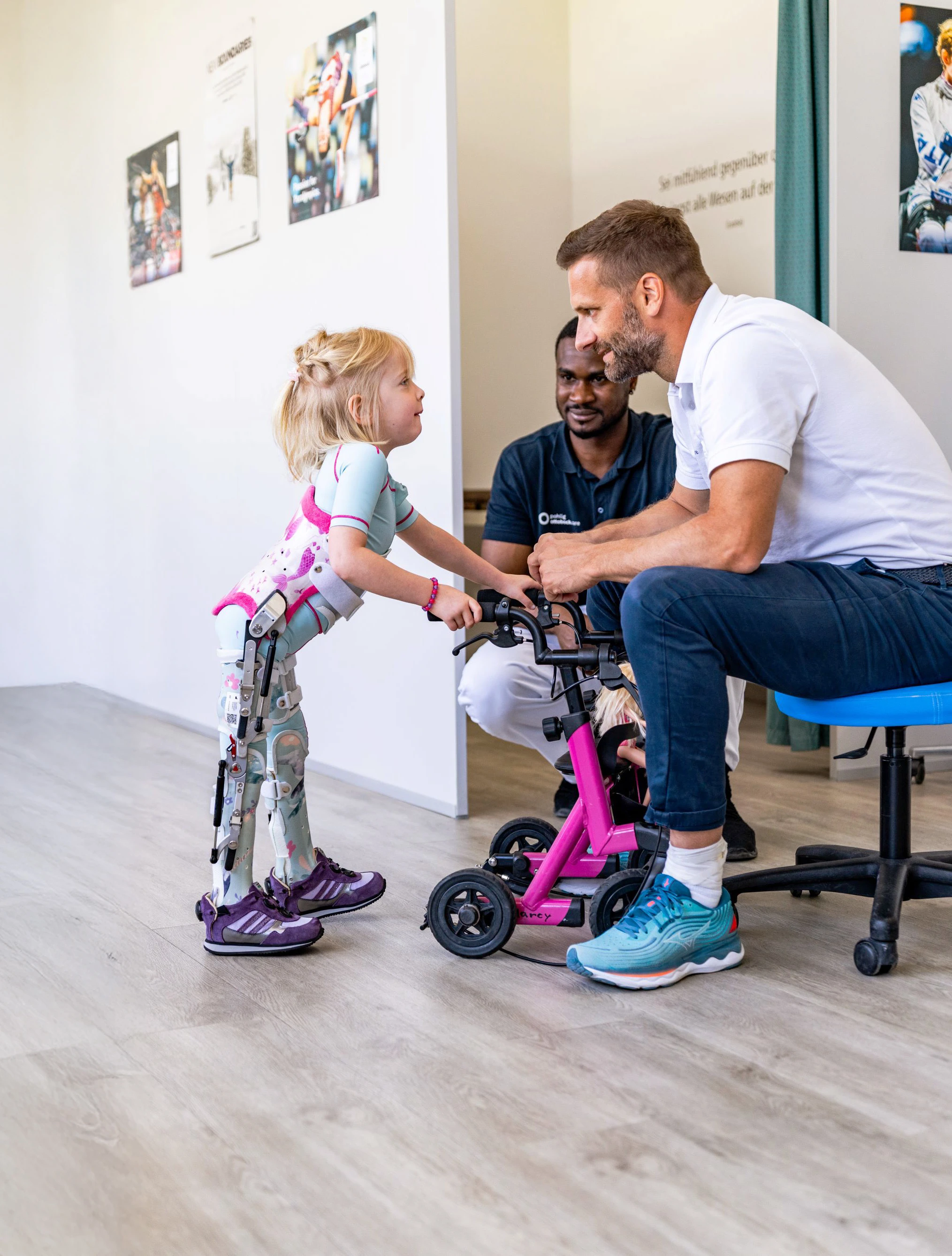 Mädchen mit Beinorthesen übt Stehen mit Orthopädietechniker.