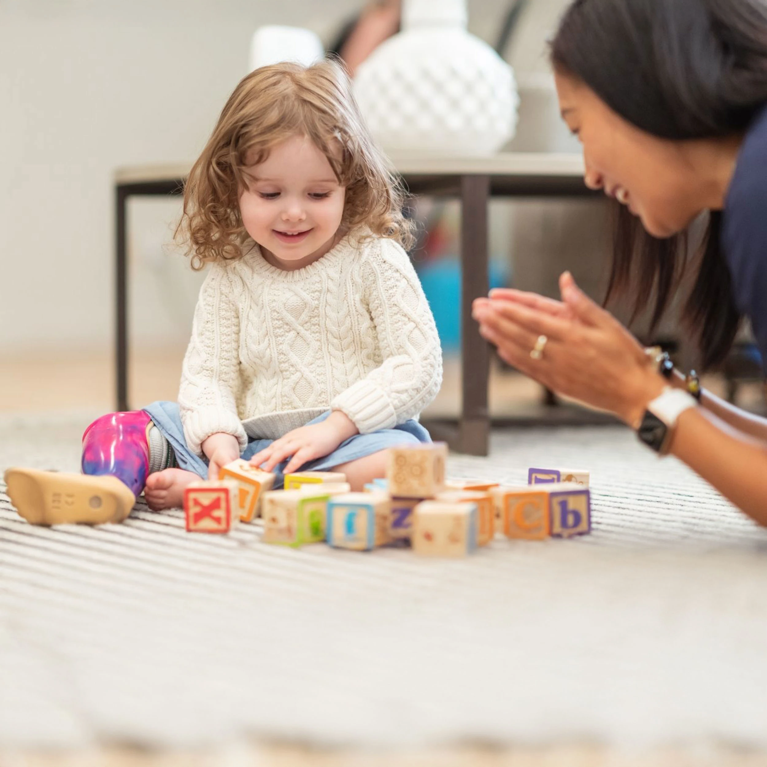 Un protésico certificado jugando con bloques de palabras con un niño en una pierna protésica