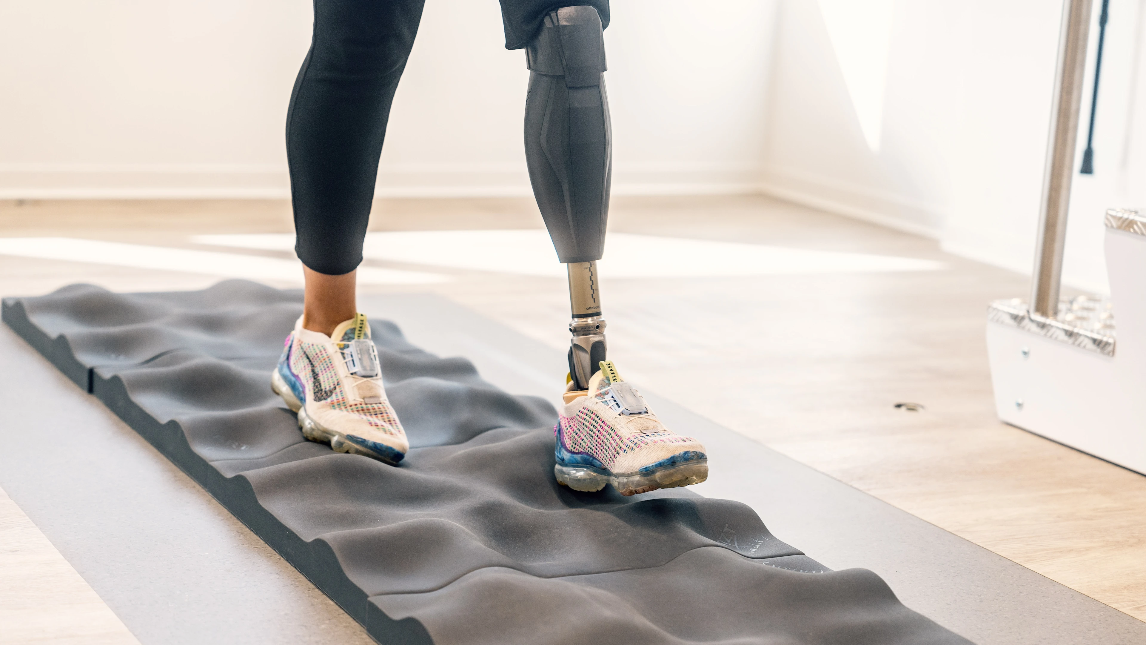 A Genium X3 user walking on a texture foam on the floor with varying slopes and uneven terrains to demonstrate the microprocessor-controlled knee's adaptability and ability to balance