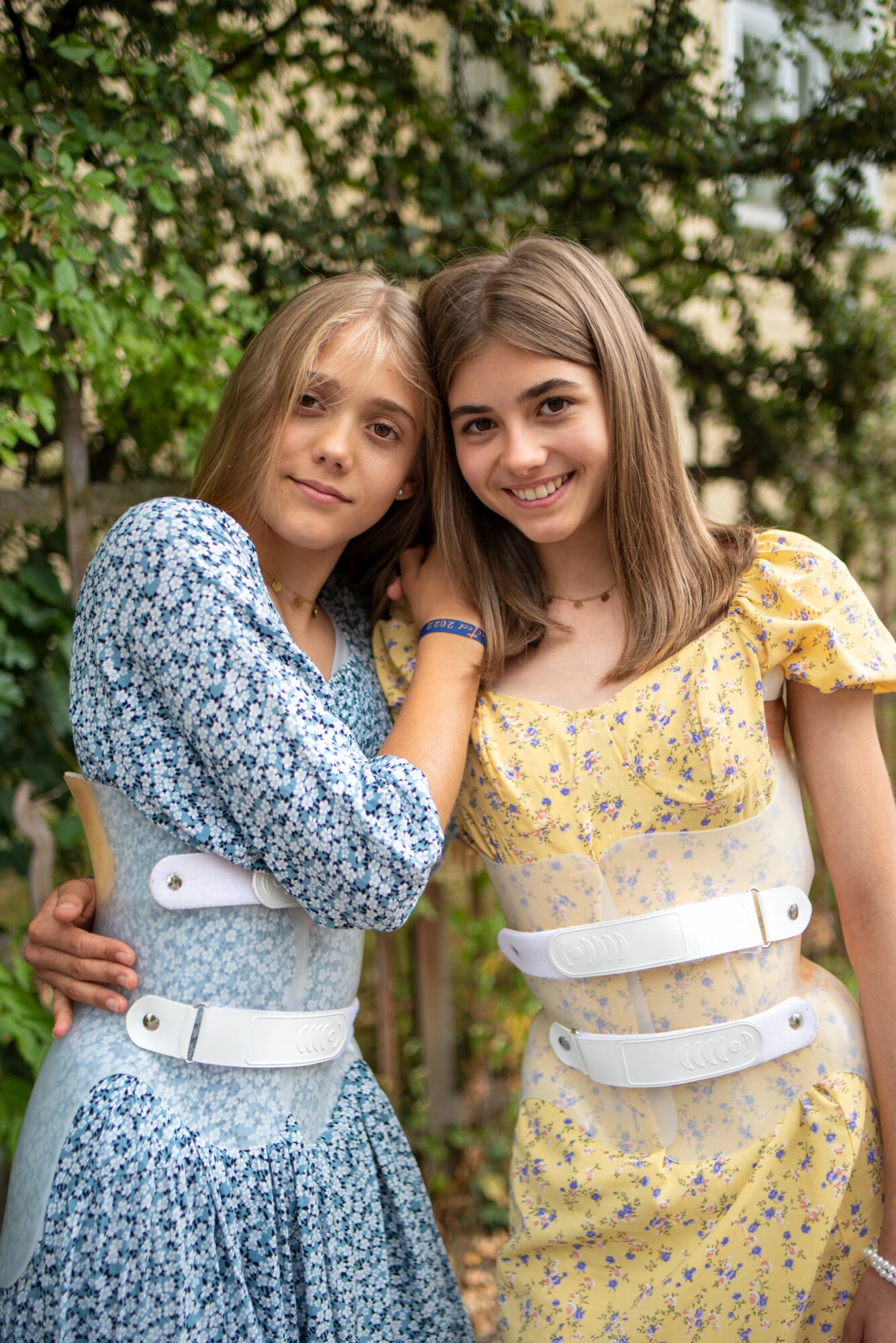 Two people wearing back braces over dresses while standing outdoors.
