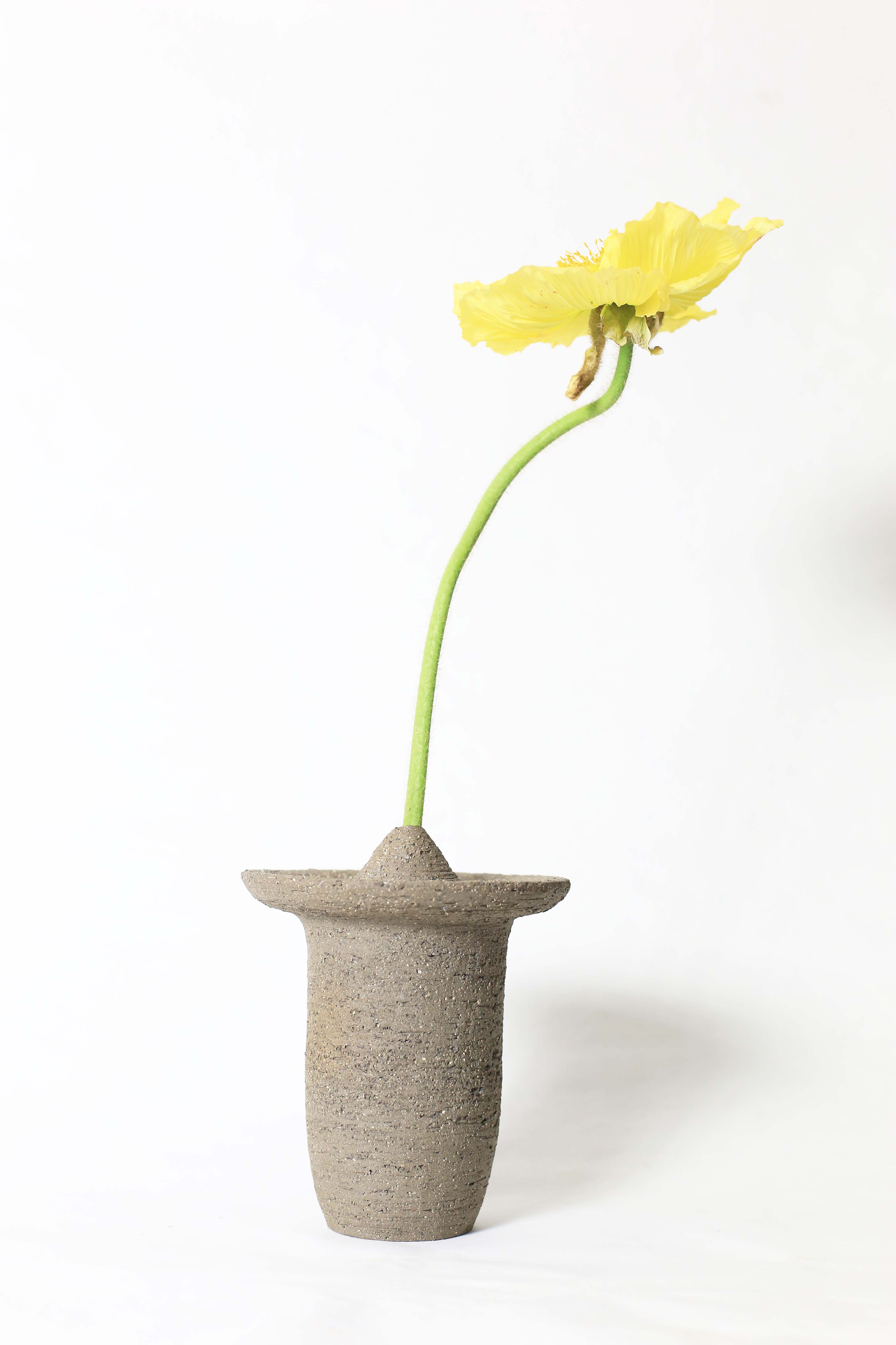 Ufo shaped gray ceramic vase with a yellow flower on a white background 3