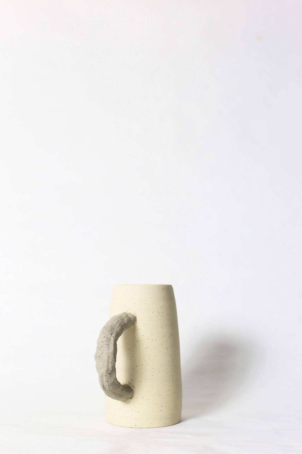 Beige ceramic jug on a white background handle forward