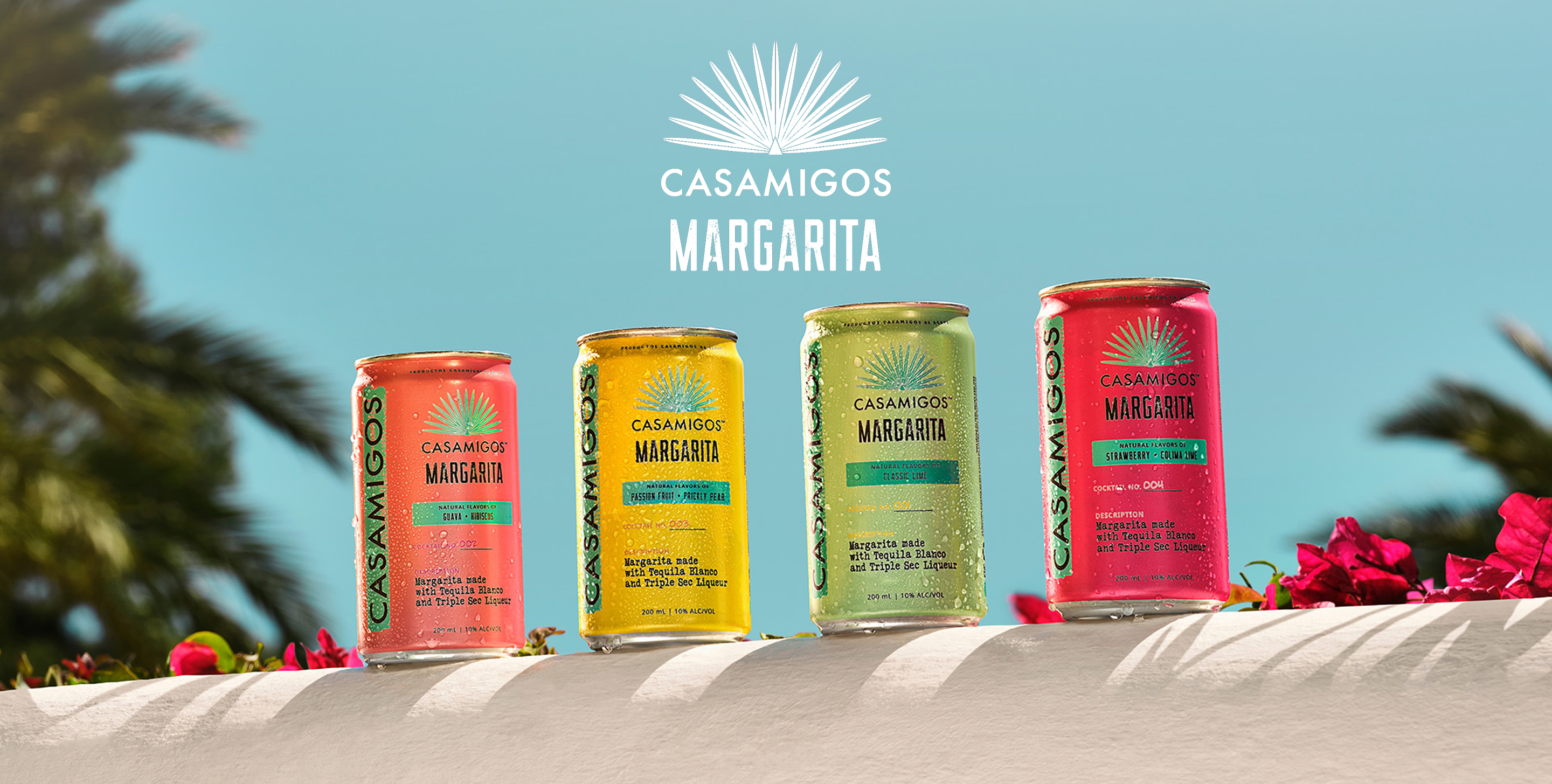 Casamigos Canned Margaritas displayed on a ledge surrounded by dark pink flowers and tropical background with palm trees.