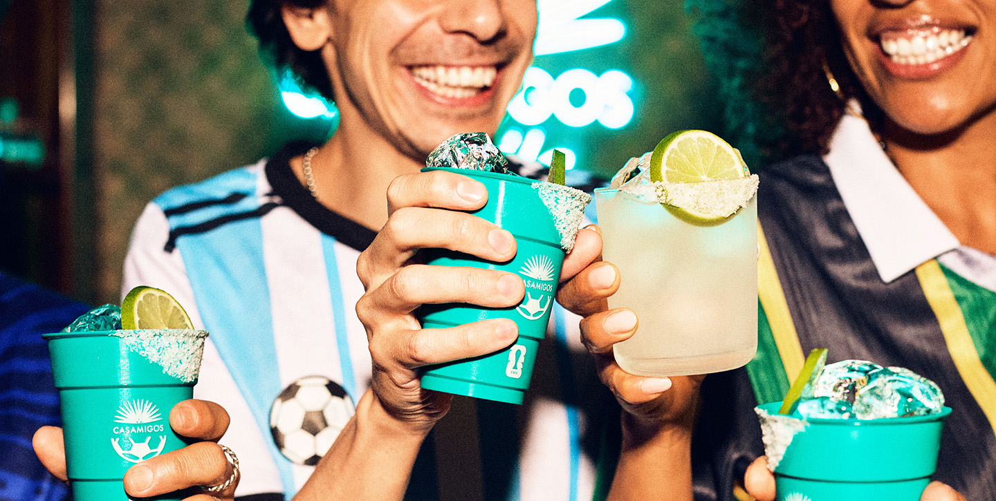 Two friends in football jersey's toasting margaritas.