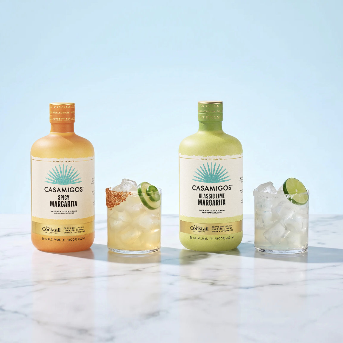 Ready-to-Serve Brandname Crafted Cocktails in Spicy Margarita and Classic Lime Margarita flavors, served on the rocks with chili-lime seasoning, lime and jalapeño garnishes, and a salted rim on white marble.