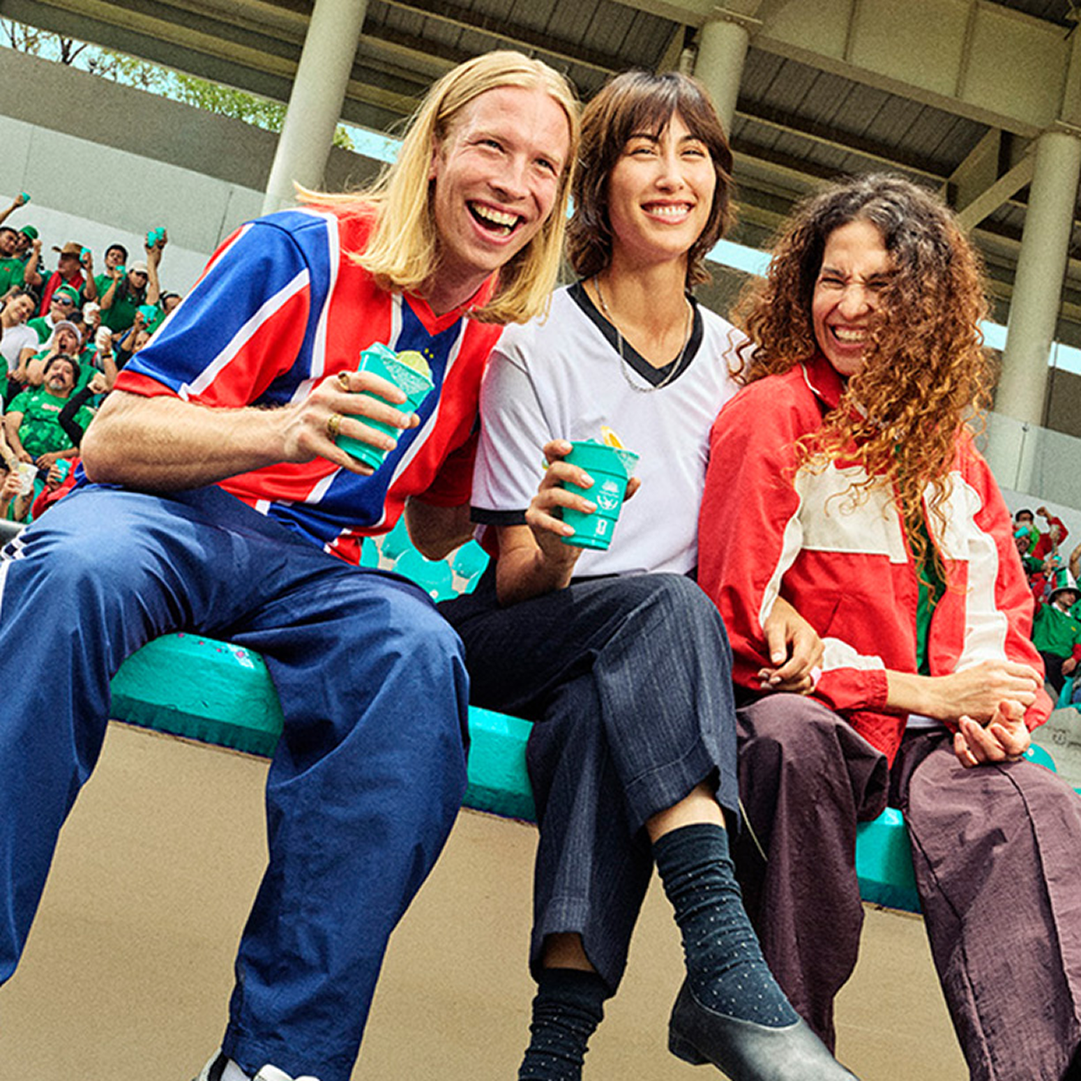 Group of friends smiling in stadium stands holding Casamigos cocktails during a soccer game.