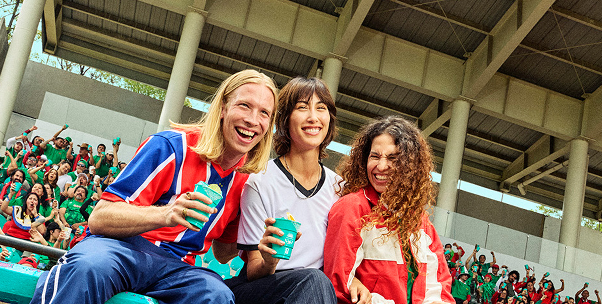 Group of friends smiling in stadium stands holding Casamigos cocktails during a soccer game.