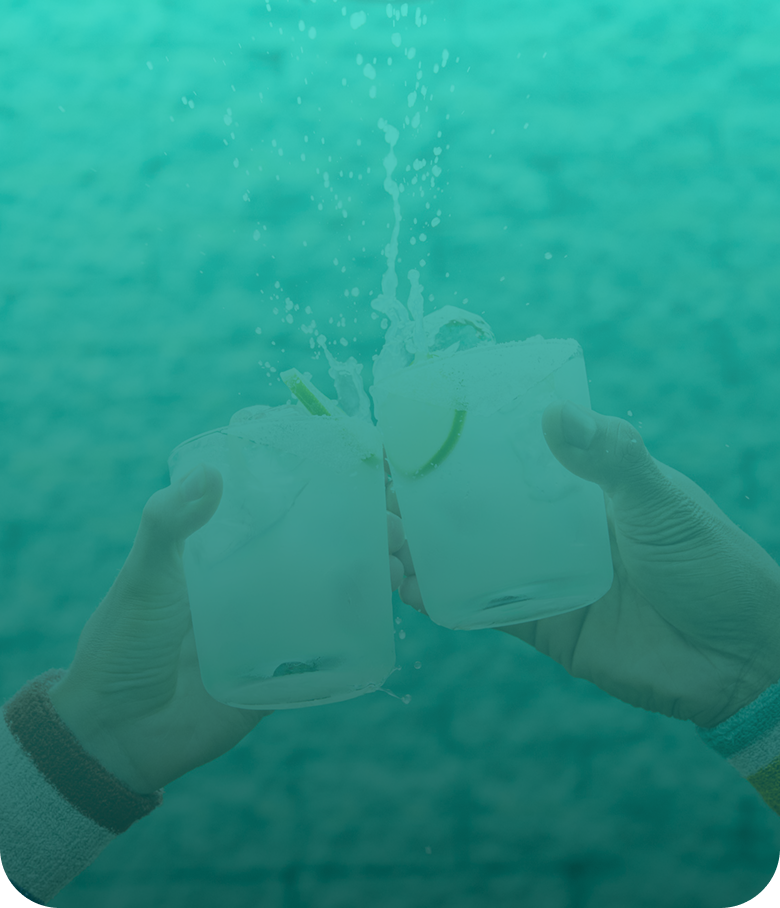 Two hands clink margaritas in rocks glasses with lime wedges, splashing against a teal background.