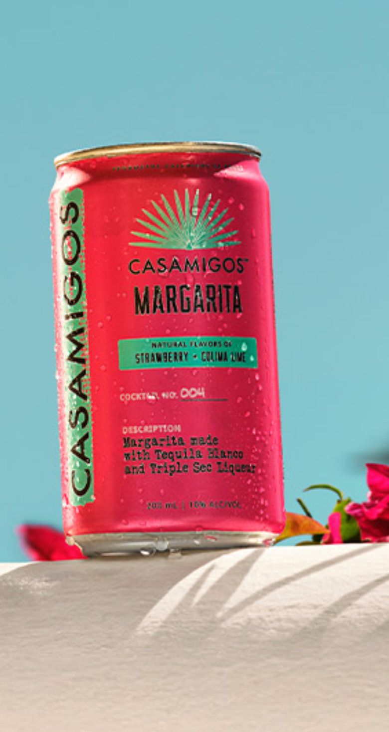Casamigos Ready to Drink Margarita on a ledge surrounded by pink flowers.