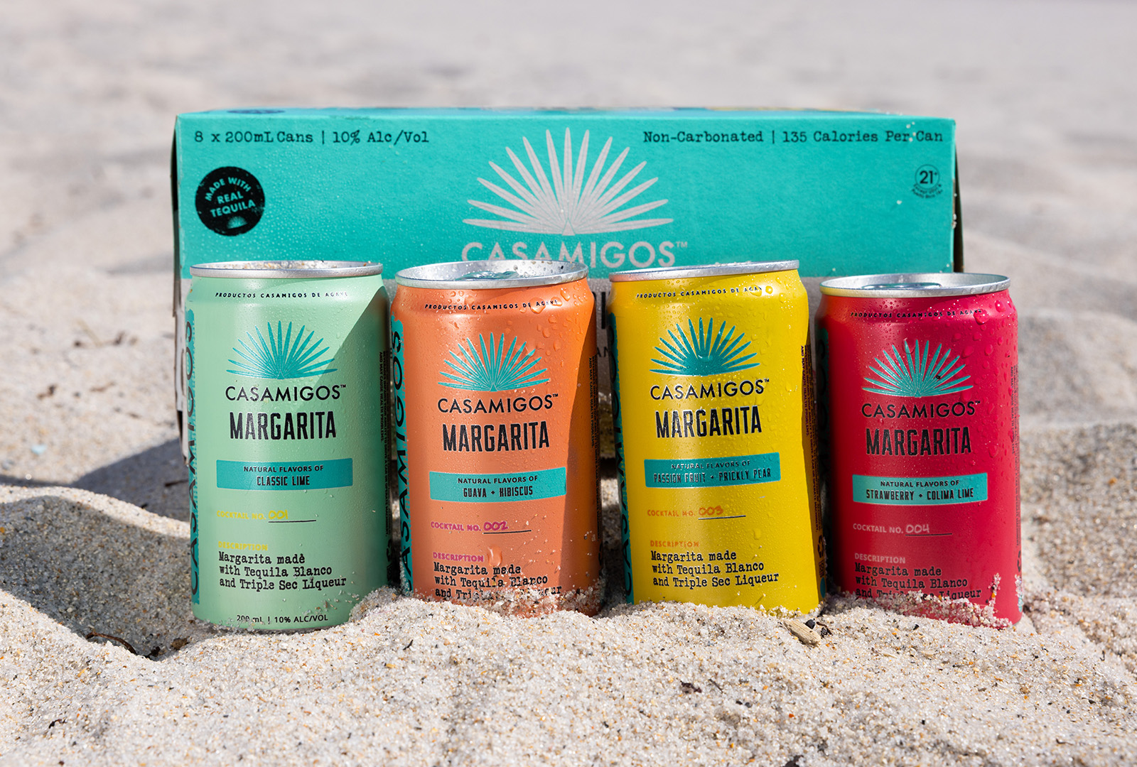 A case of Casamigos ready to drink cans nested in the sand at the beach.  