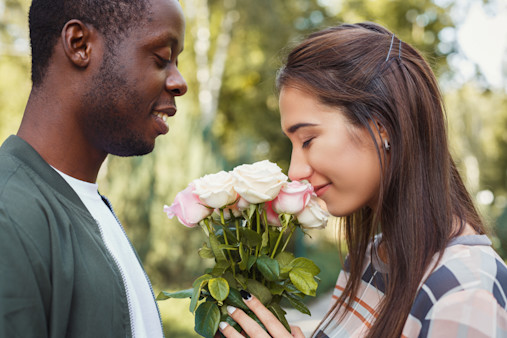 Man giving flowers for his beautiful girlfriend, having anniversary date in park, copy space