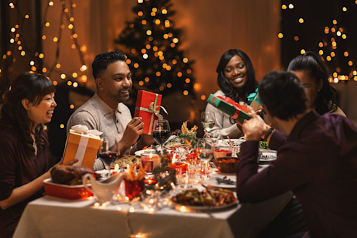 concept de fête, fête et fête - groupe multiethnique d'amis heureux qui dînent à noël et donnent des cadeaux à la maison