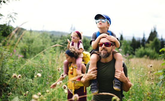 Family with small children hiking outdoors in summer nature.