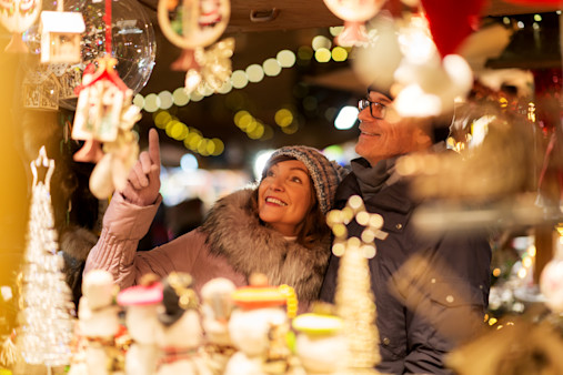 shopping, winter holidays and people concept - happy senior couple at christmas market souvenir shop on town hall square in tallinn, estonia