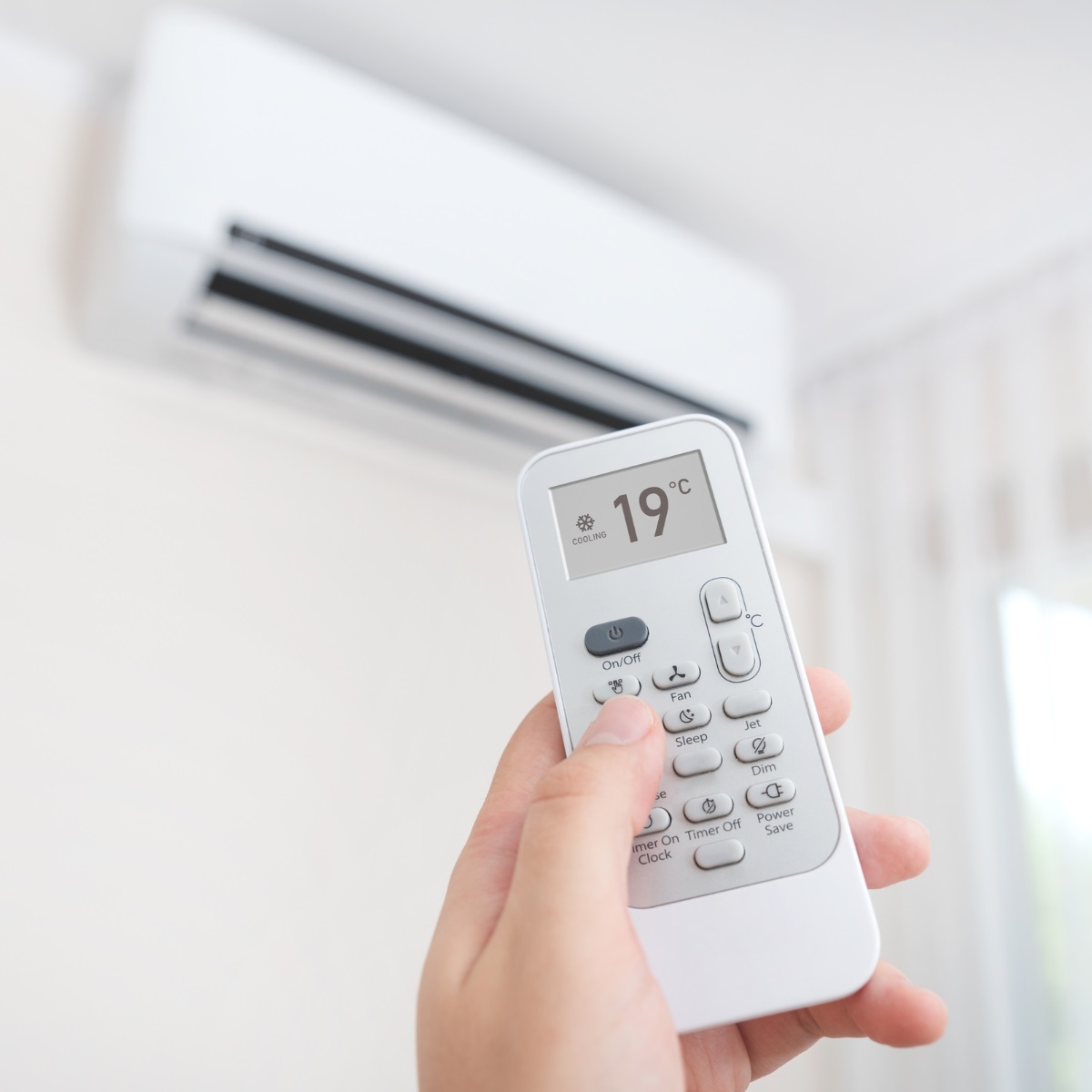 A person controlling their heat pump with a remote.