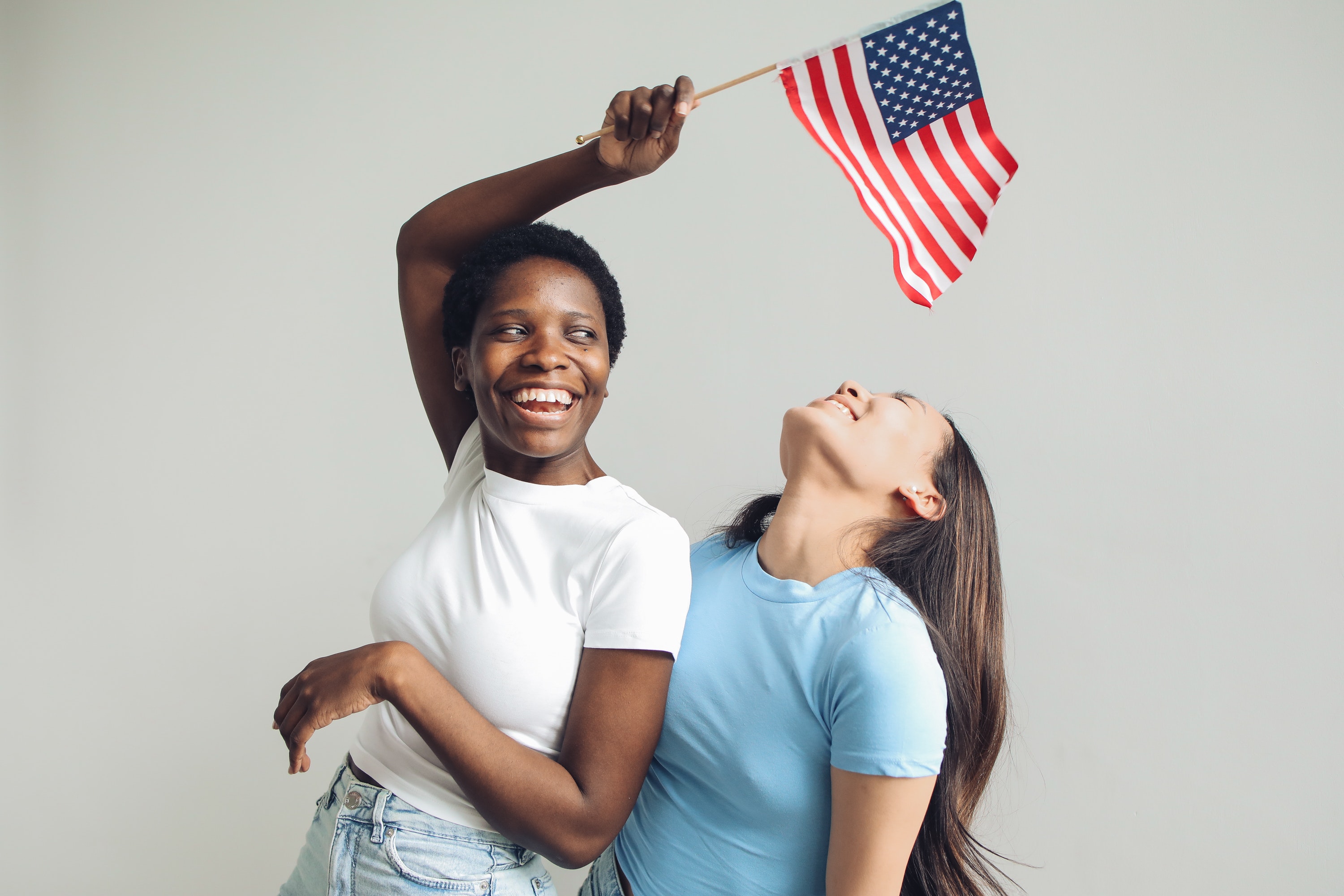 two women laughing holding the american flag