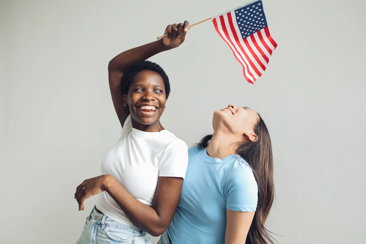 two women laughing holding the american flag