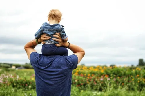 Father holding his baby on his shoulders while in a grassy field discussing what is probate.