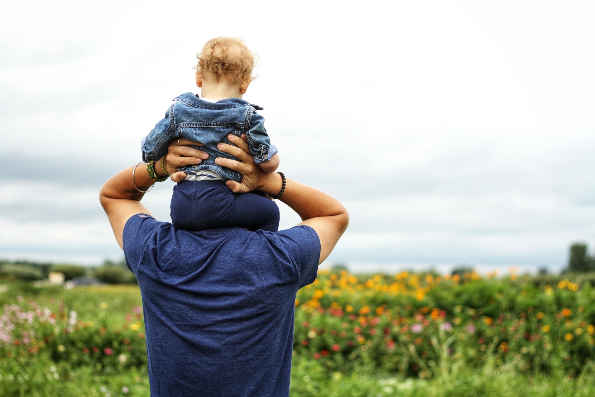 Father holding his baby on his shoulders while in a grassy field discussing what is probate.