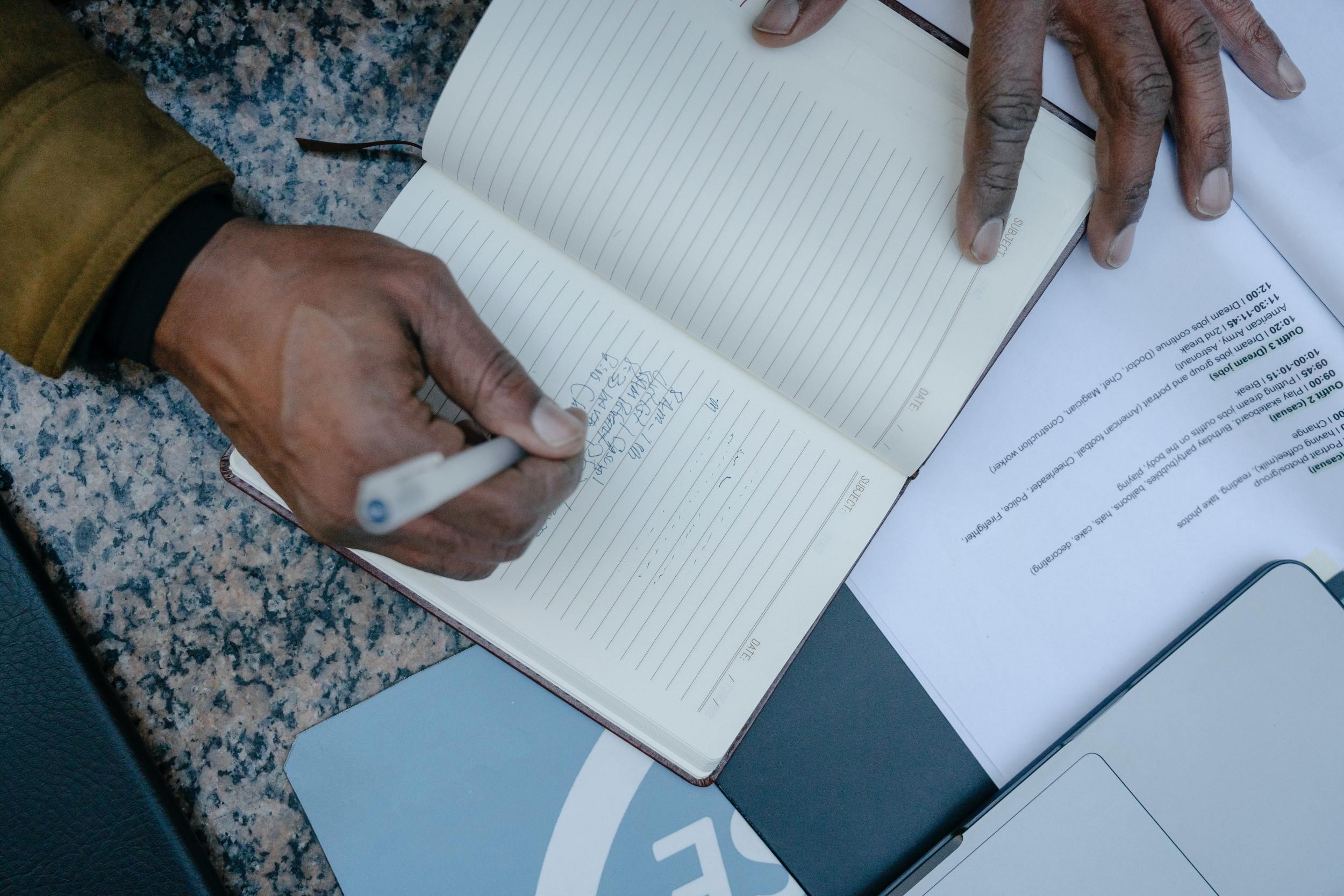 Person writing down notes while researching the cremation process.