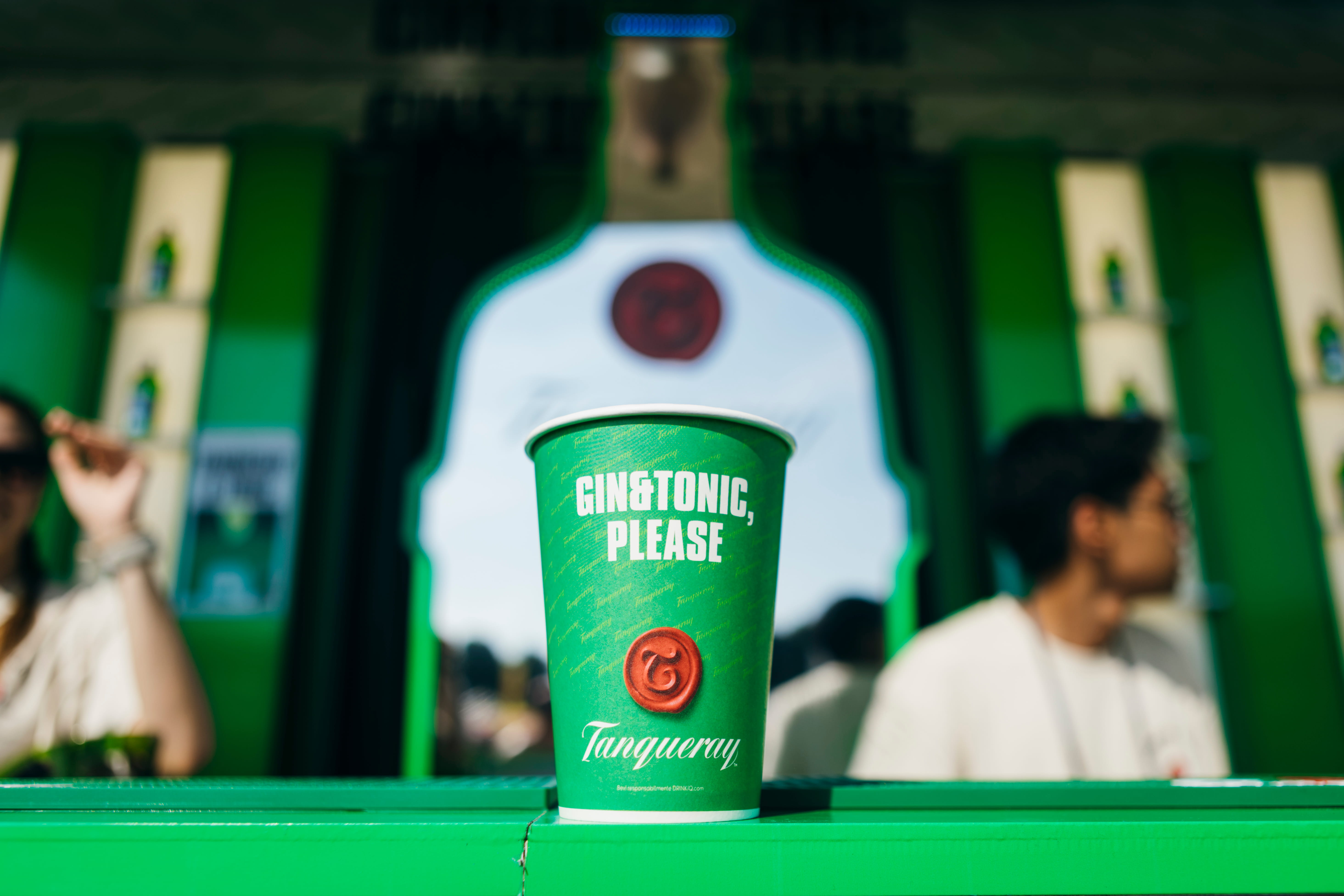 Bicchiere verde con gin and tonic e tanqueray tand sullo sfondo