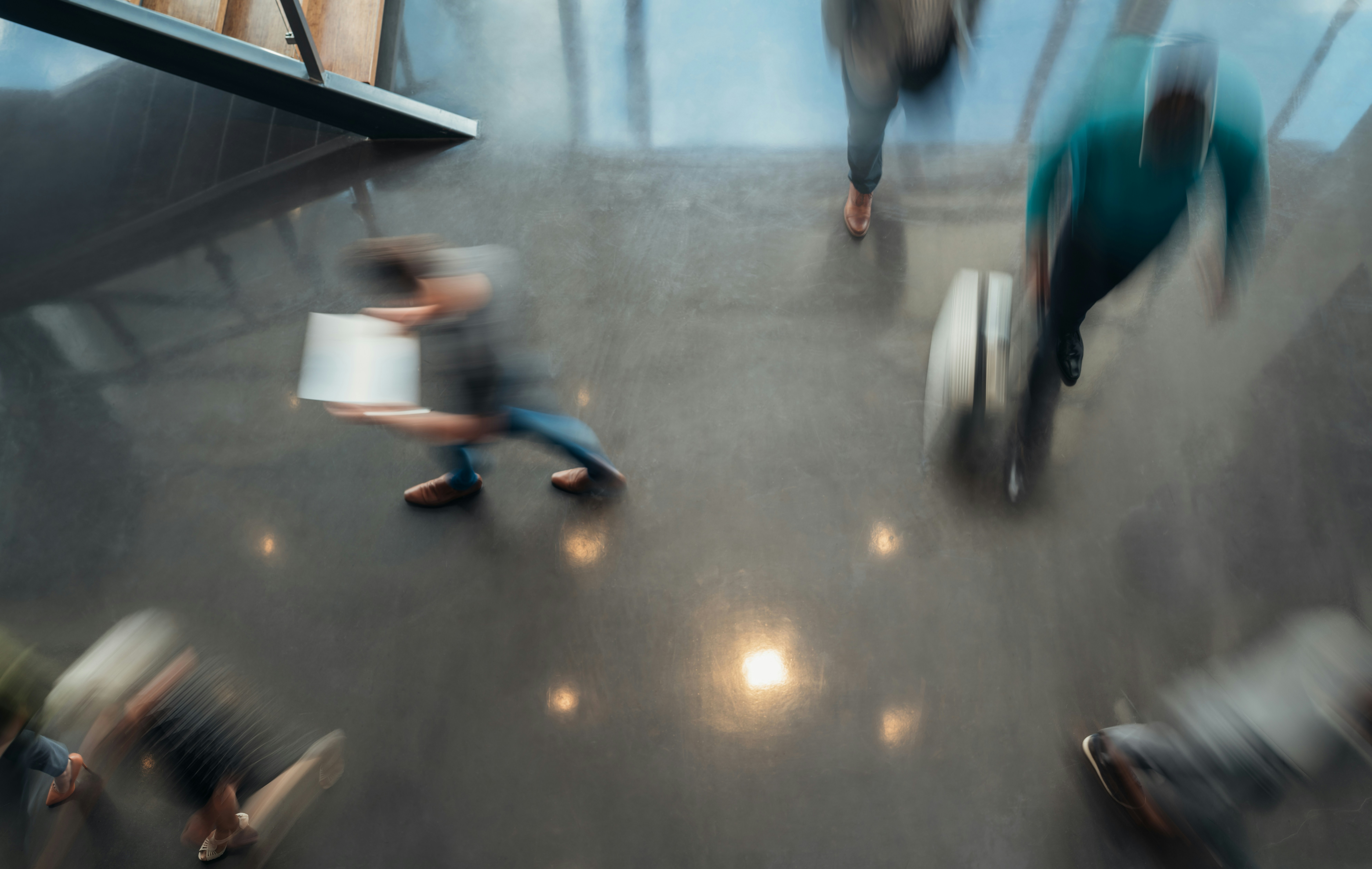 This image appears to show an overhead view of a busy indoor lobby or hallway with people walking past in a motion blur