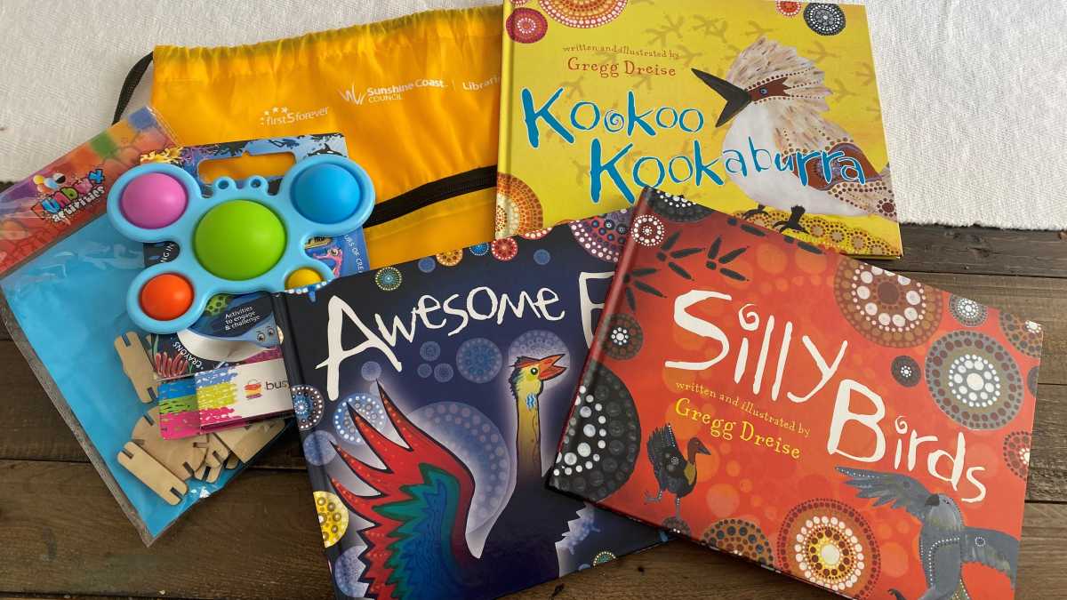A flat lay image of three children's books: Mad Magpie, Silly Birds & Kookoo Kookaburra and a yellow bag with children's toys.
